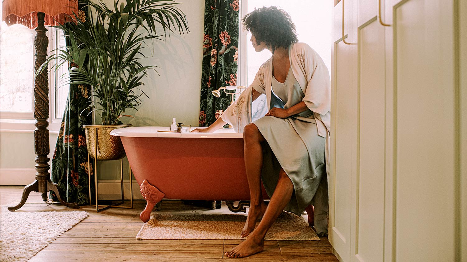 A woman tests bath water temperature