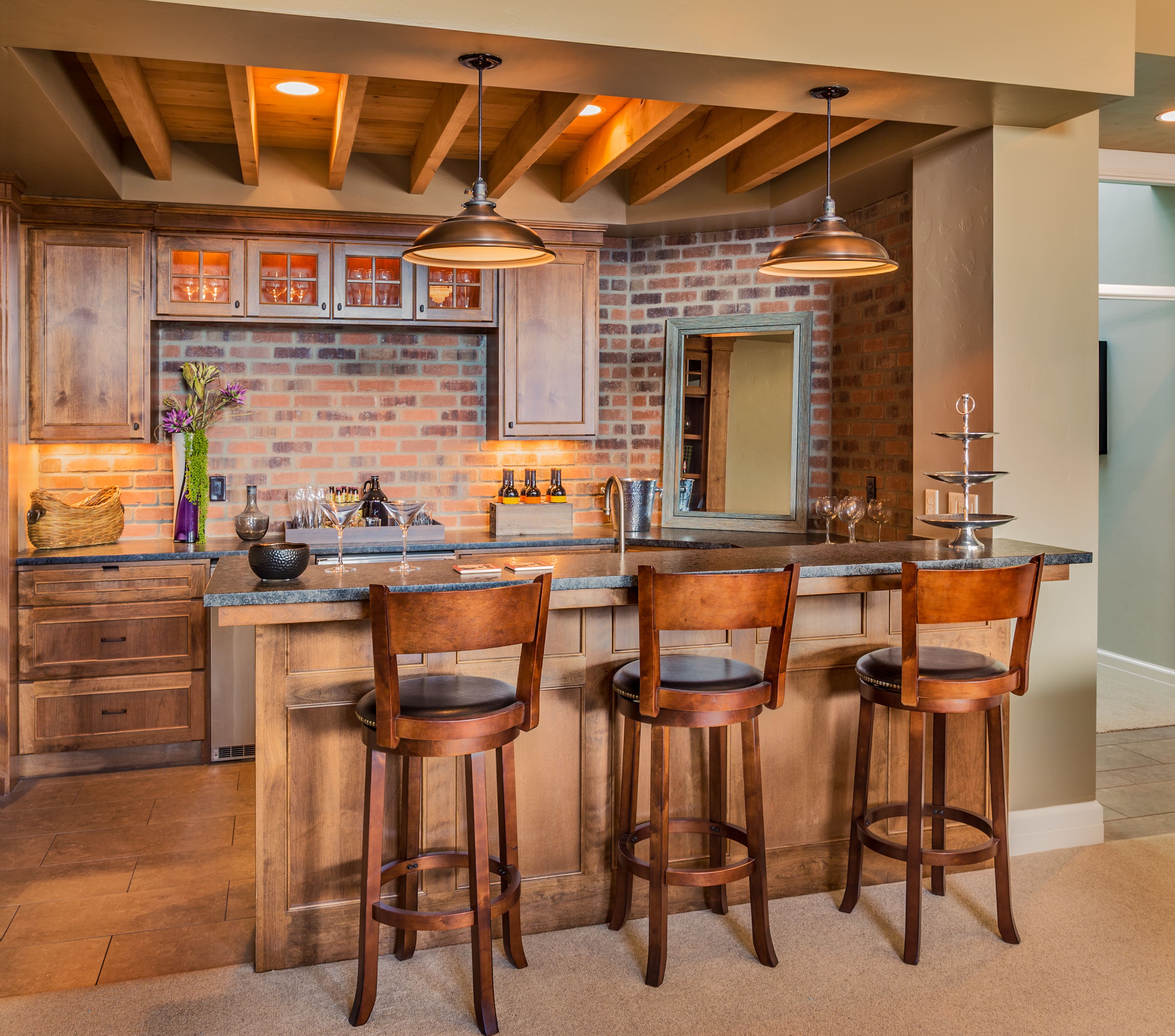 Wood basement wet bar with exposed brick, wood details, and matching seating