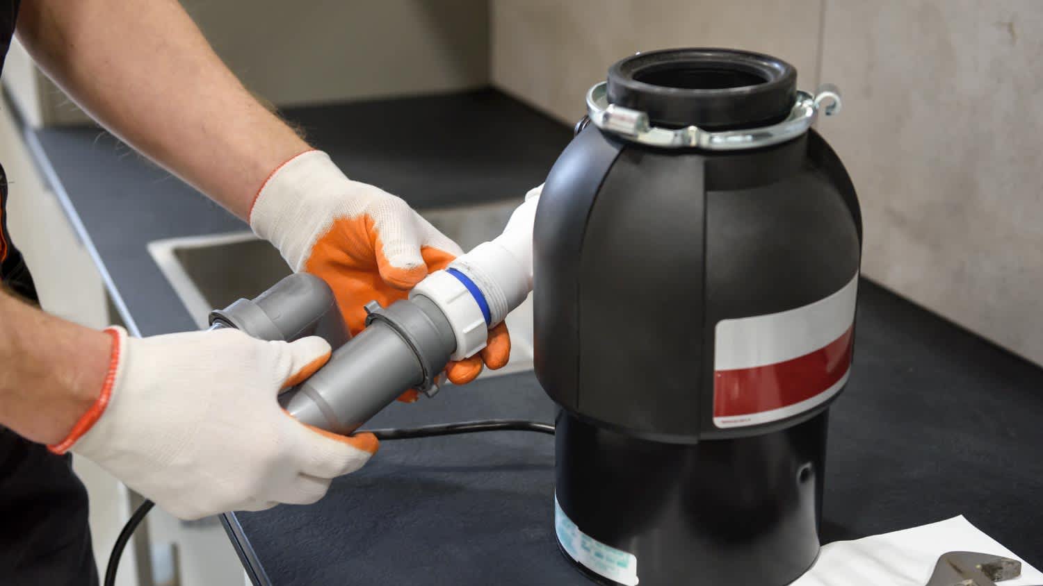 A worker installing a household waste shredder