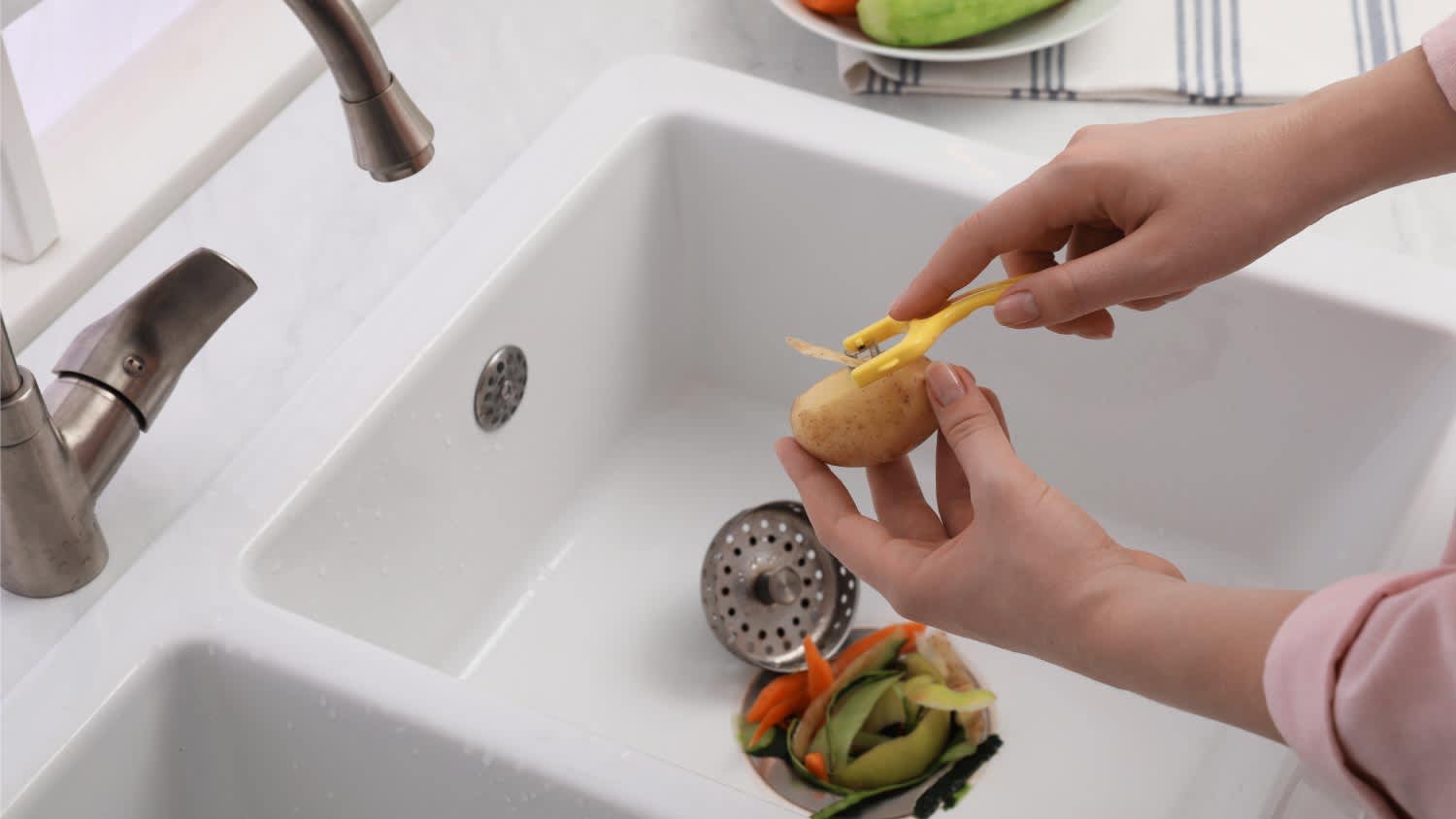 Woman peeling potato over kitchen sink