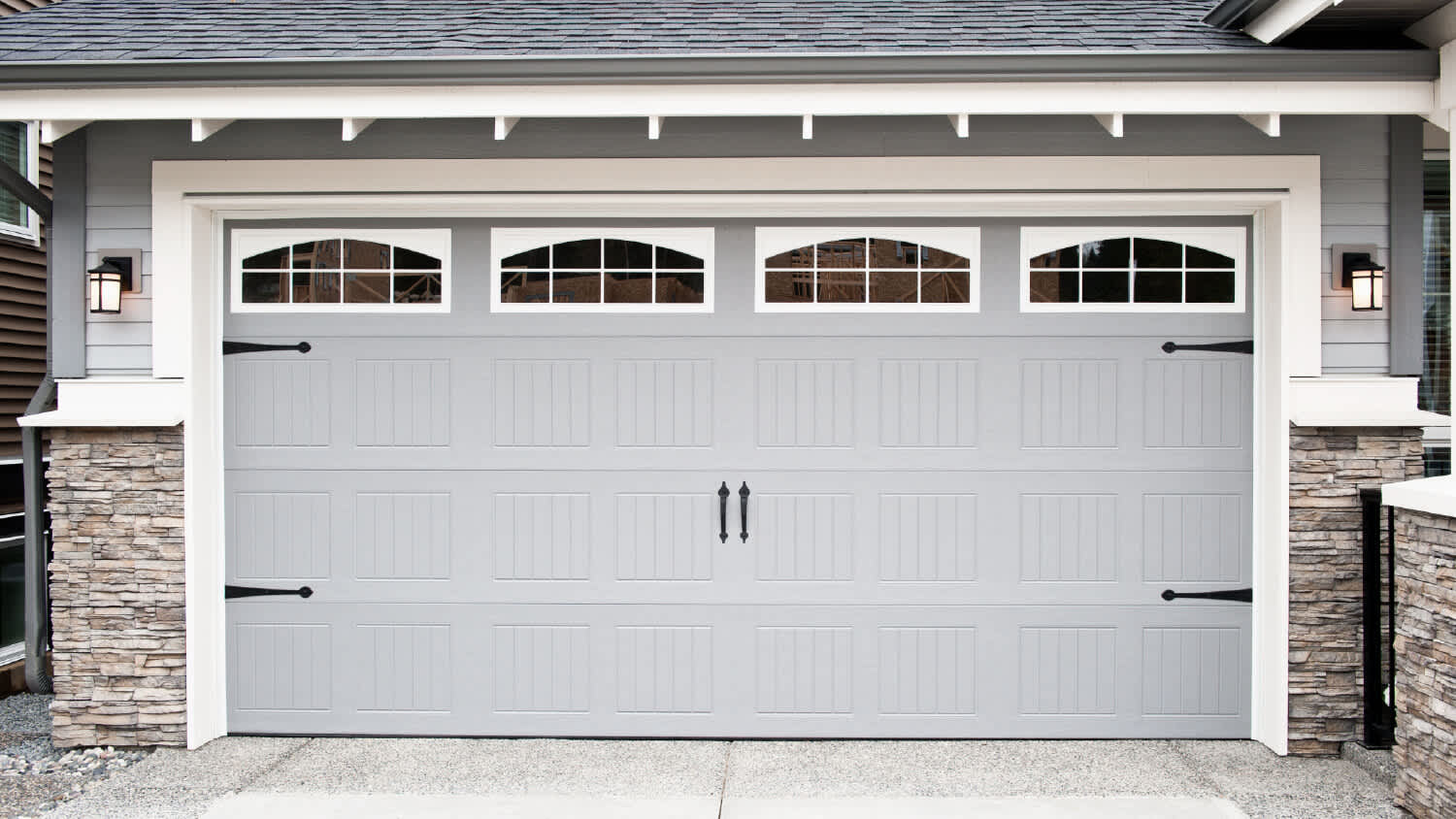 gray vinyl garage door with stone accents on exterior walls