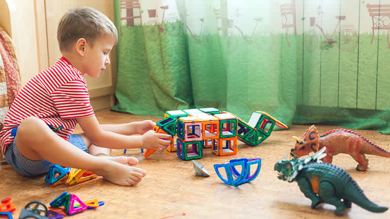 A kid sitting on a cork floor while playing with toys