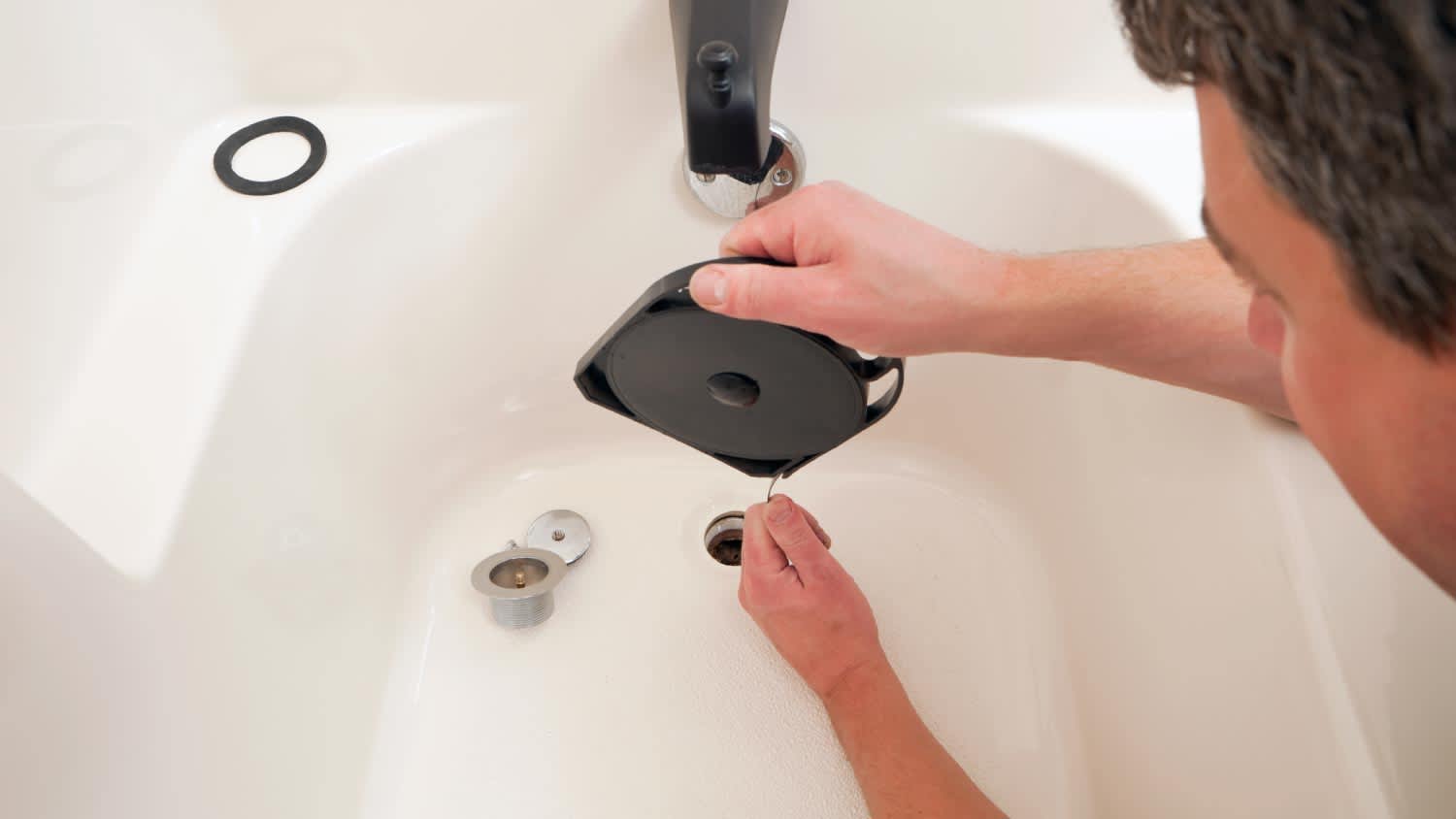 Plumber unclogging bathtub drain