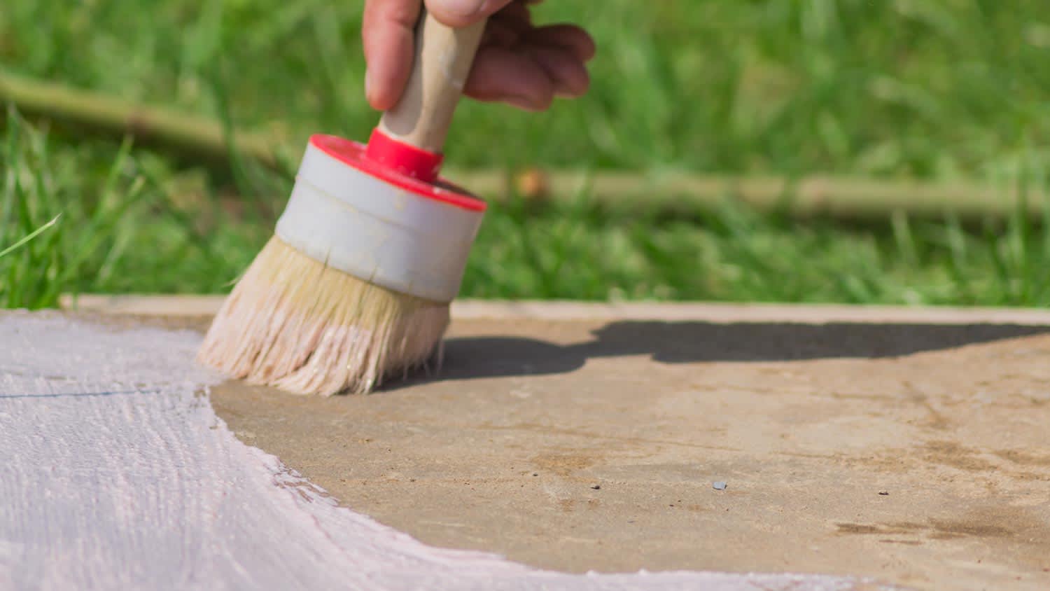 Close-up of a hand applying concrete stain