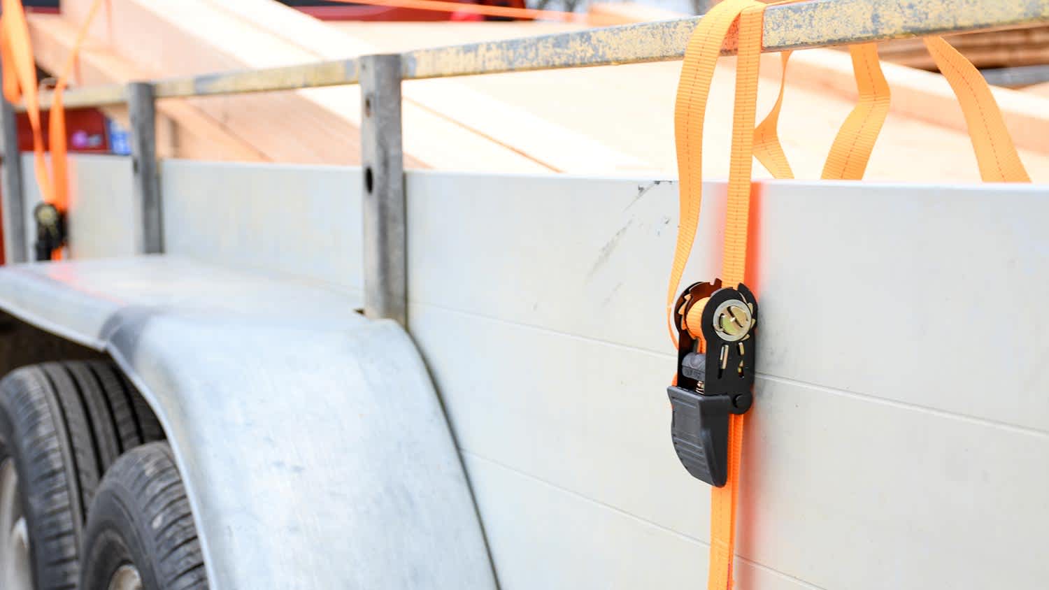 An orange ratchet strap on a trailer for safely moving stuff