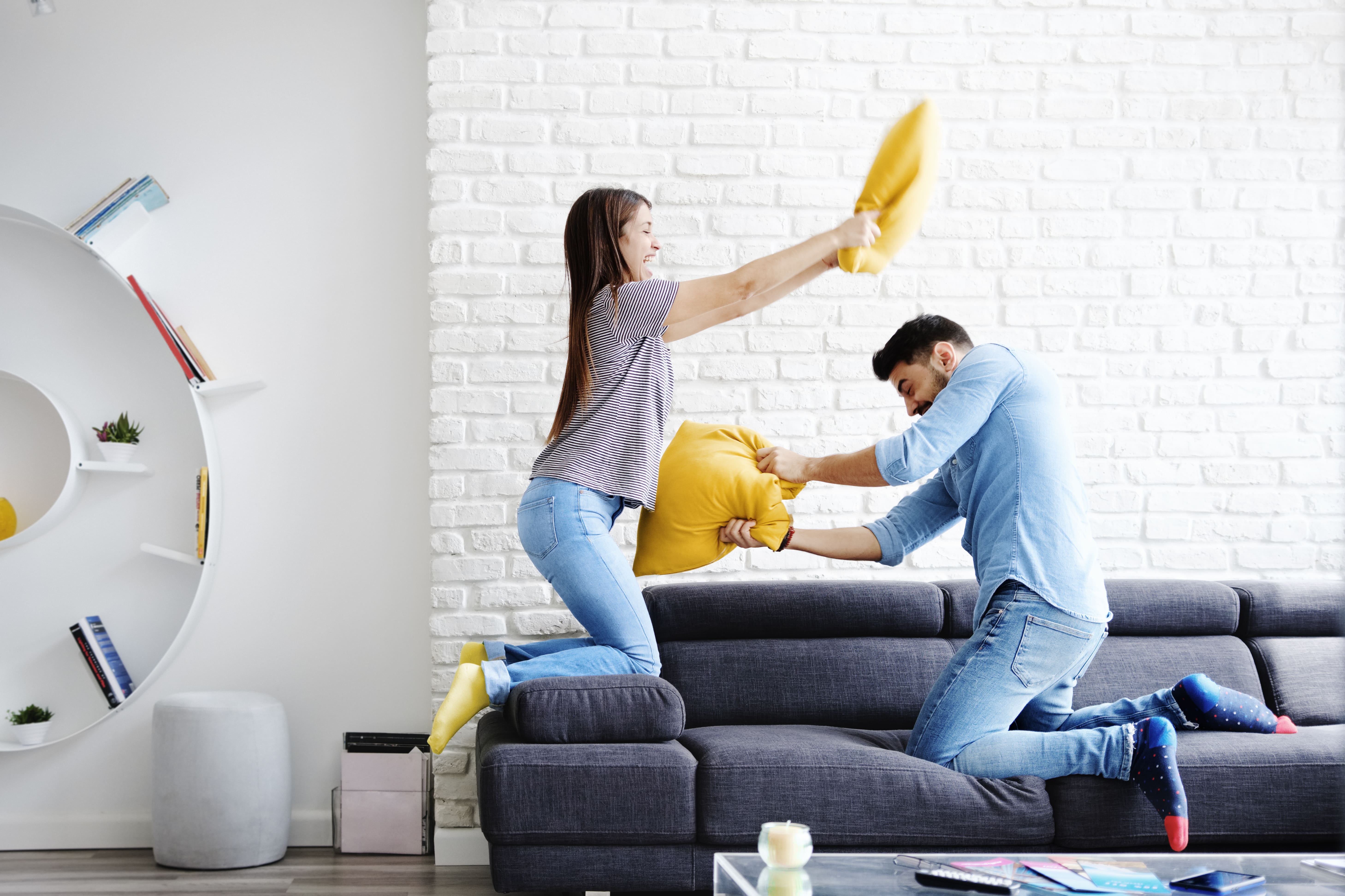 A couple having a pillow fight in a modern living room