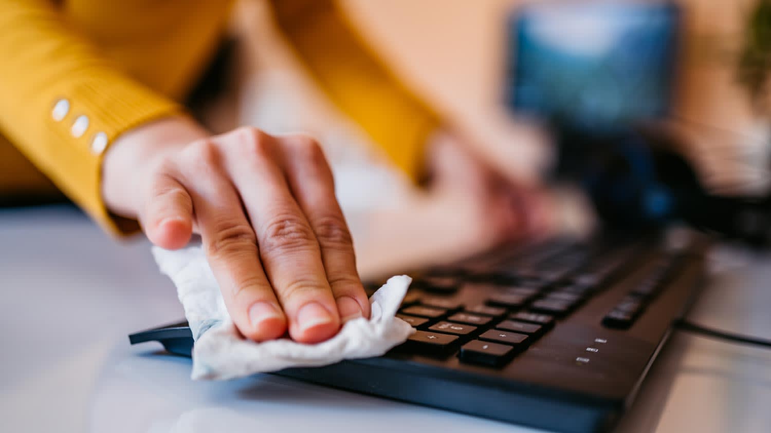A woman disinfecting a computer keyboard