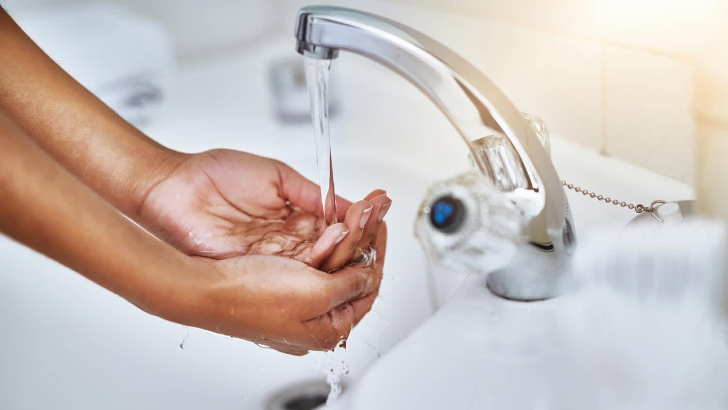 A woman washing her hands in a bathroom sink