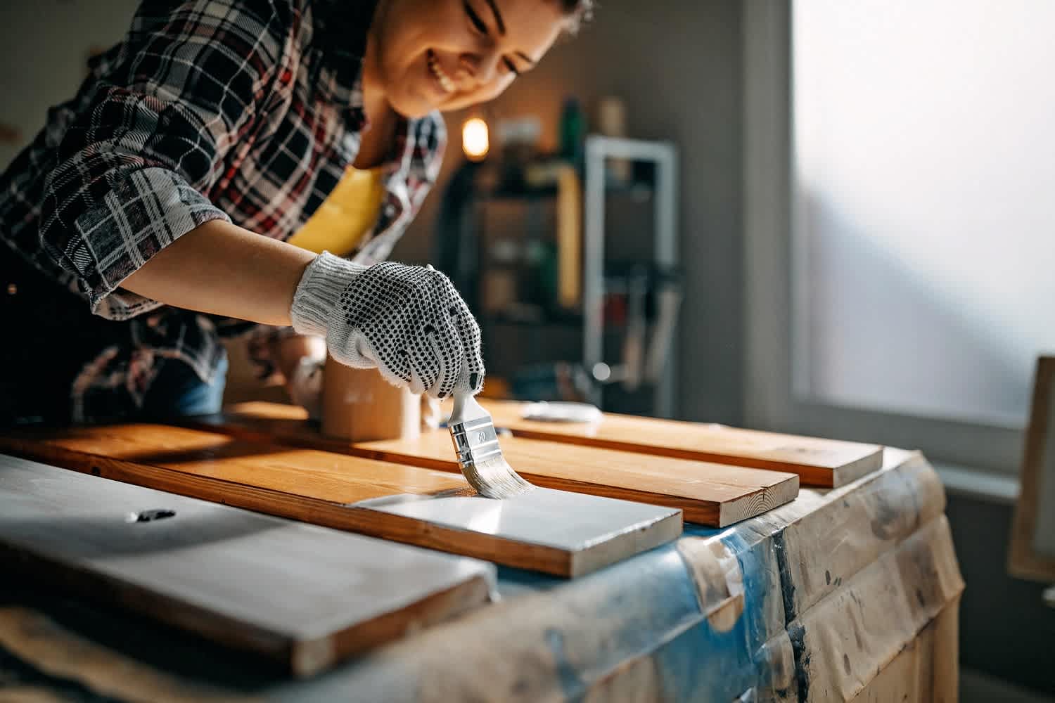 Woman painting over stained wood plank in garage