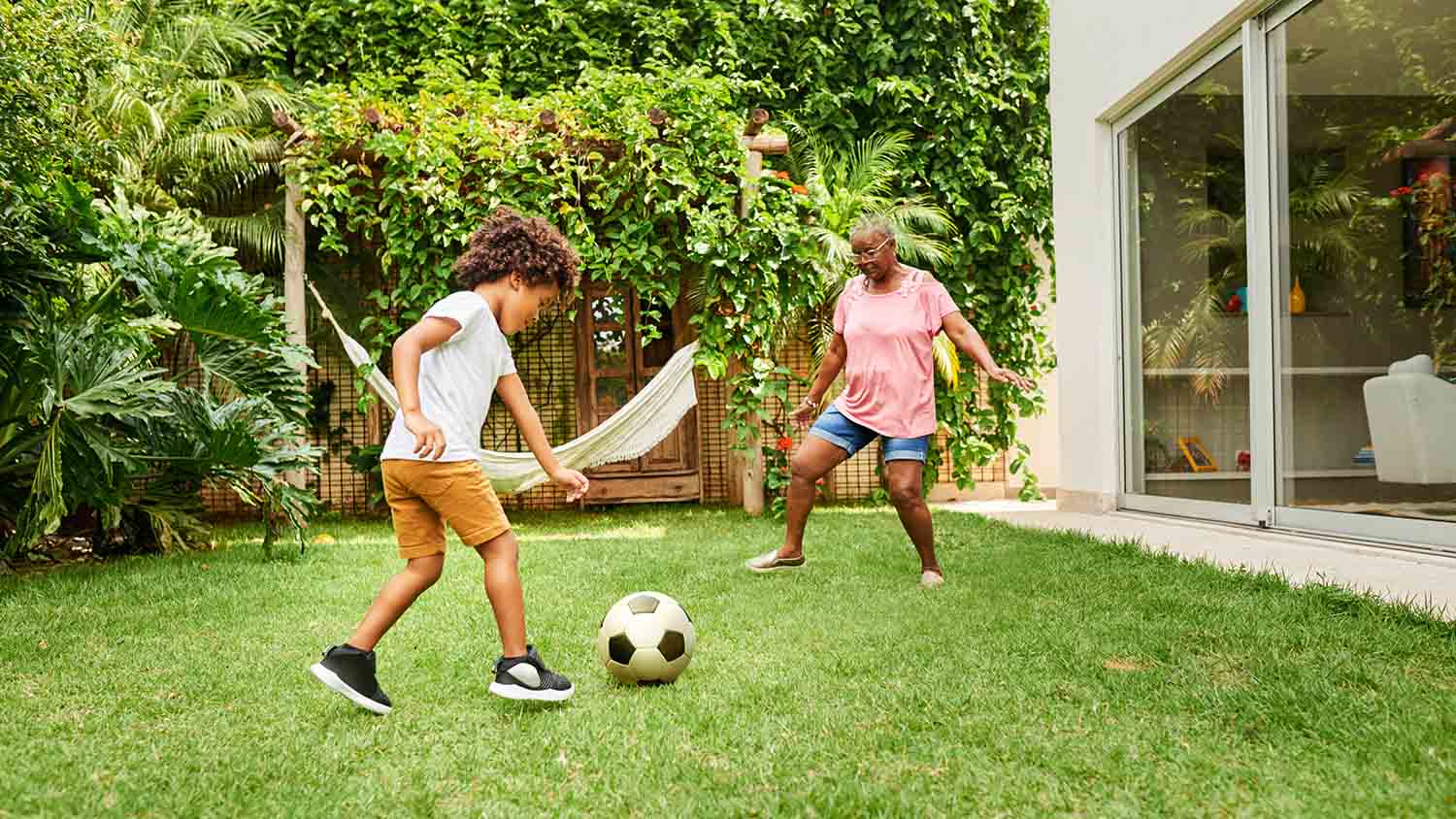 grandmother and boy playing soccer in yard