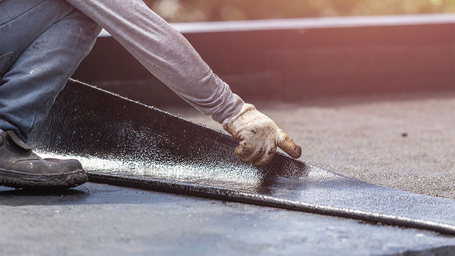 worker installing rubber material on roof