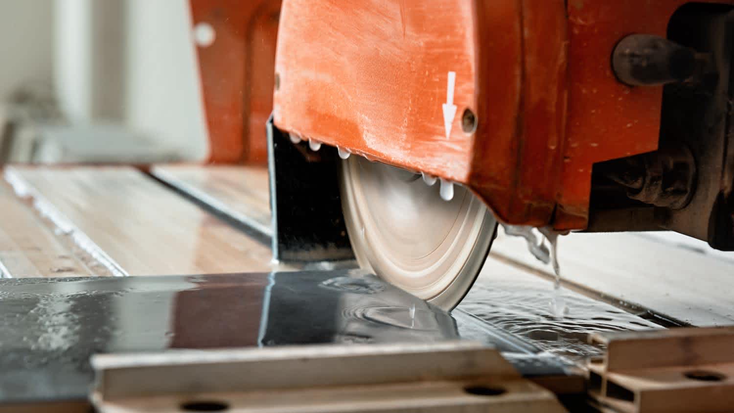 A worker cutting tile using a wet saw