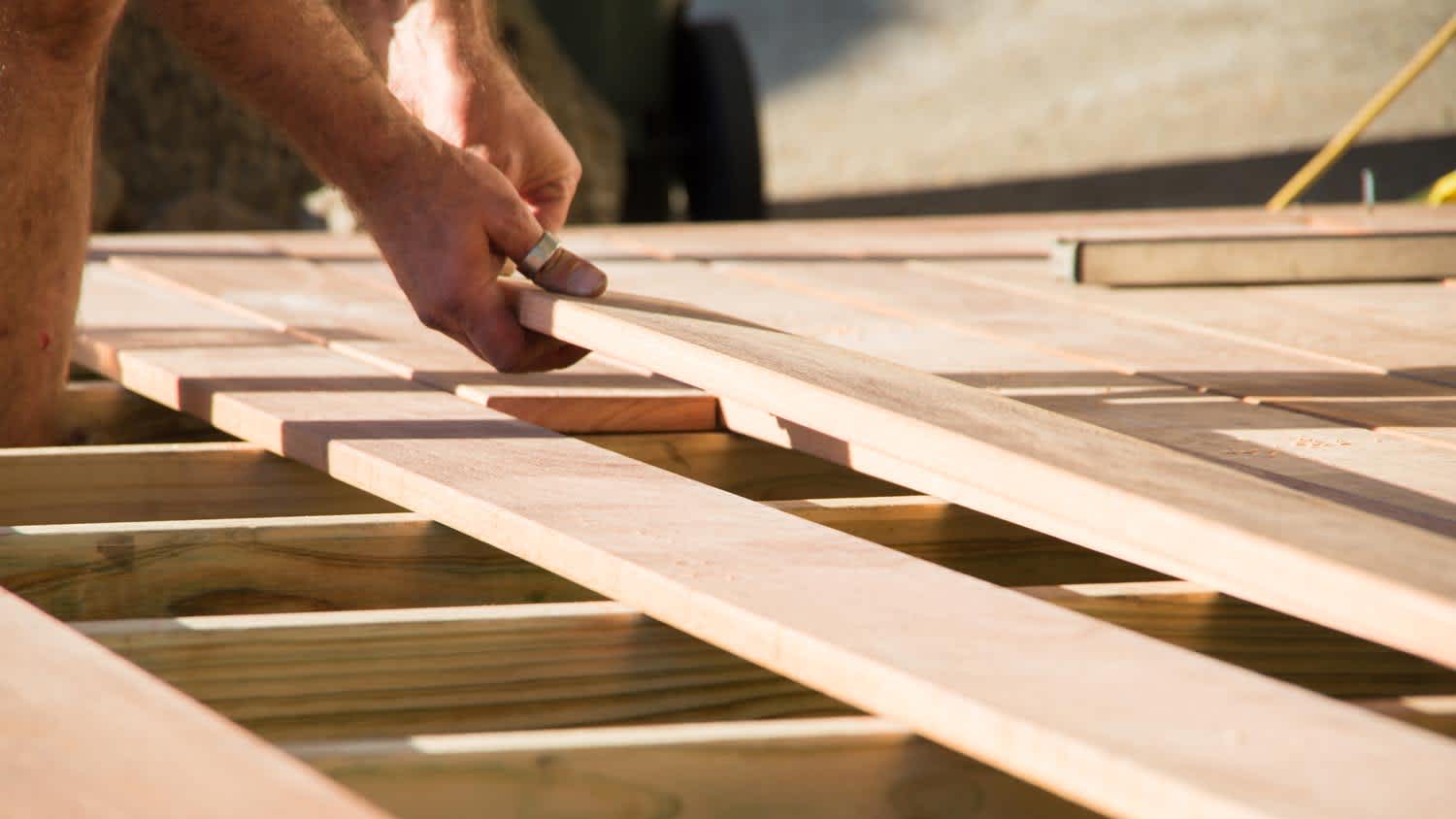 A man installing new wooden boards on deck