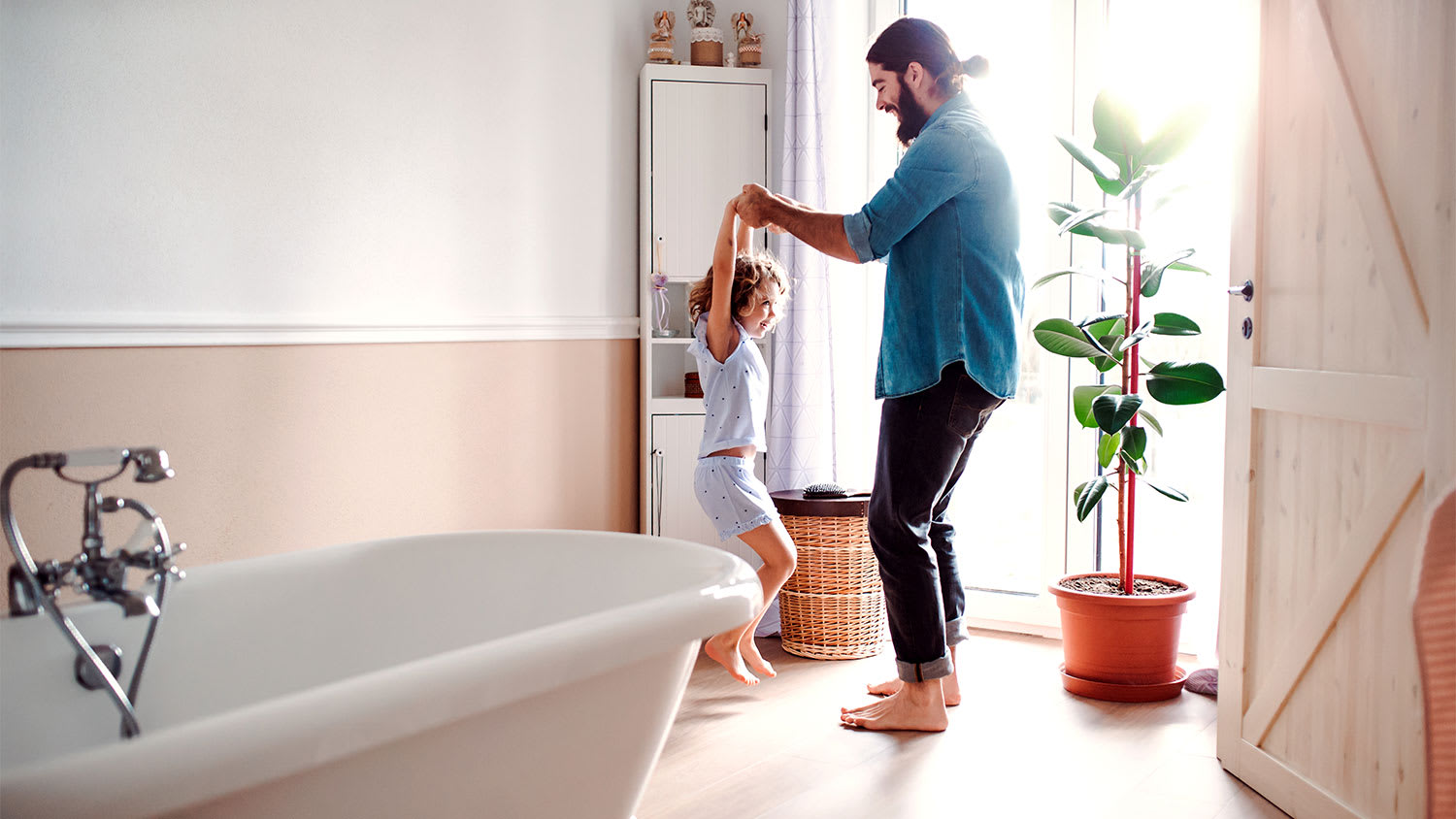 A father and daughter play in a bathroom