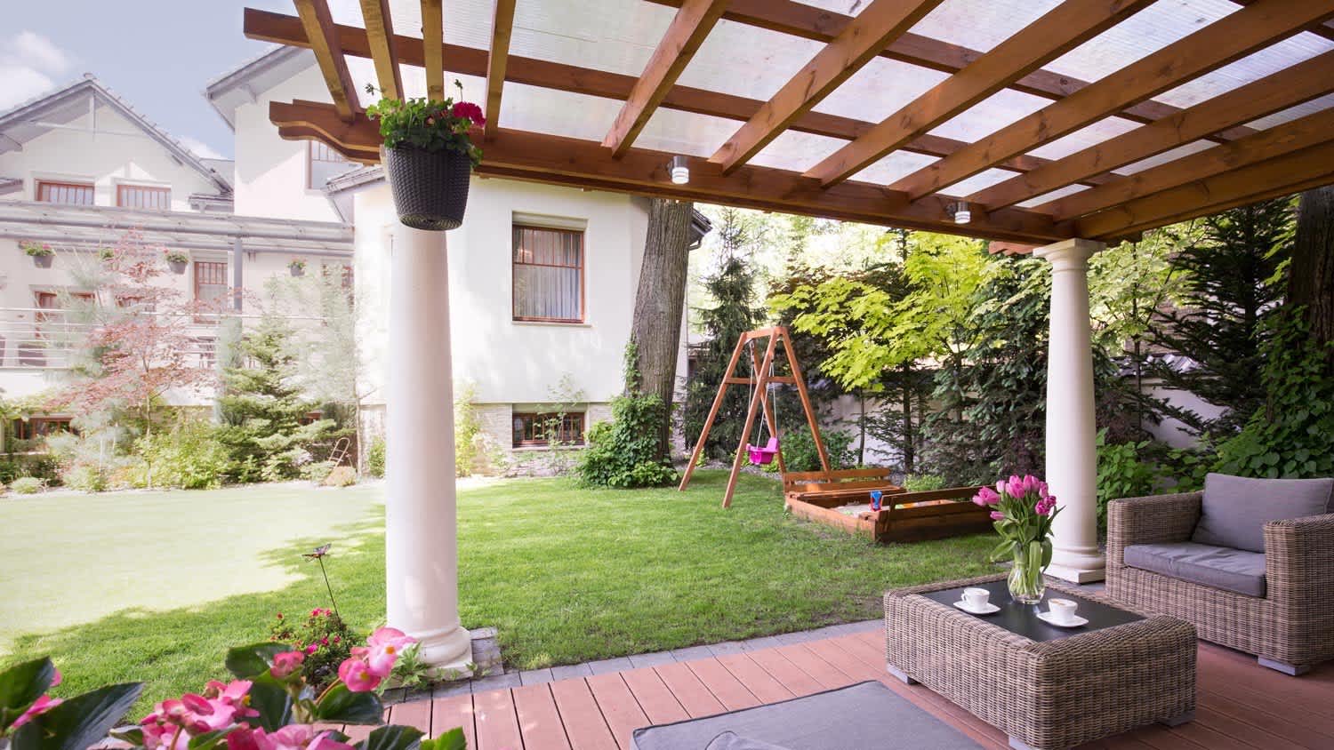 A patio in a backyard with a wooden pergola