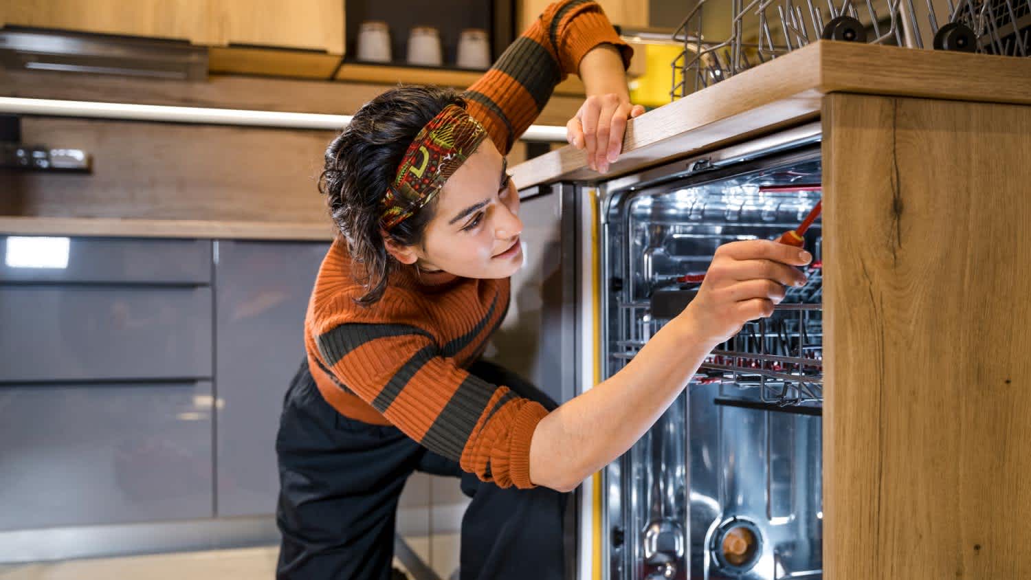 A woman installing a new dishwasher