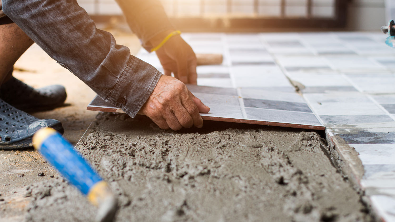 Detail of a professional installing tiles on the floor