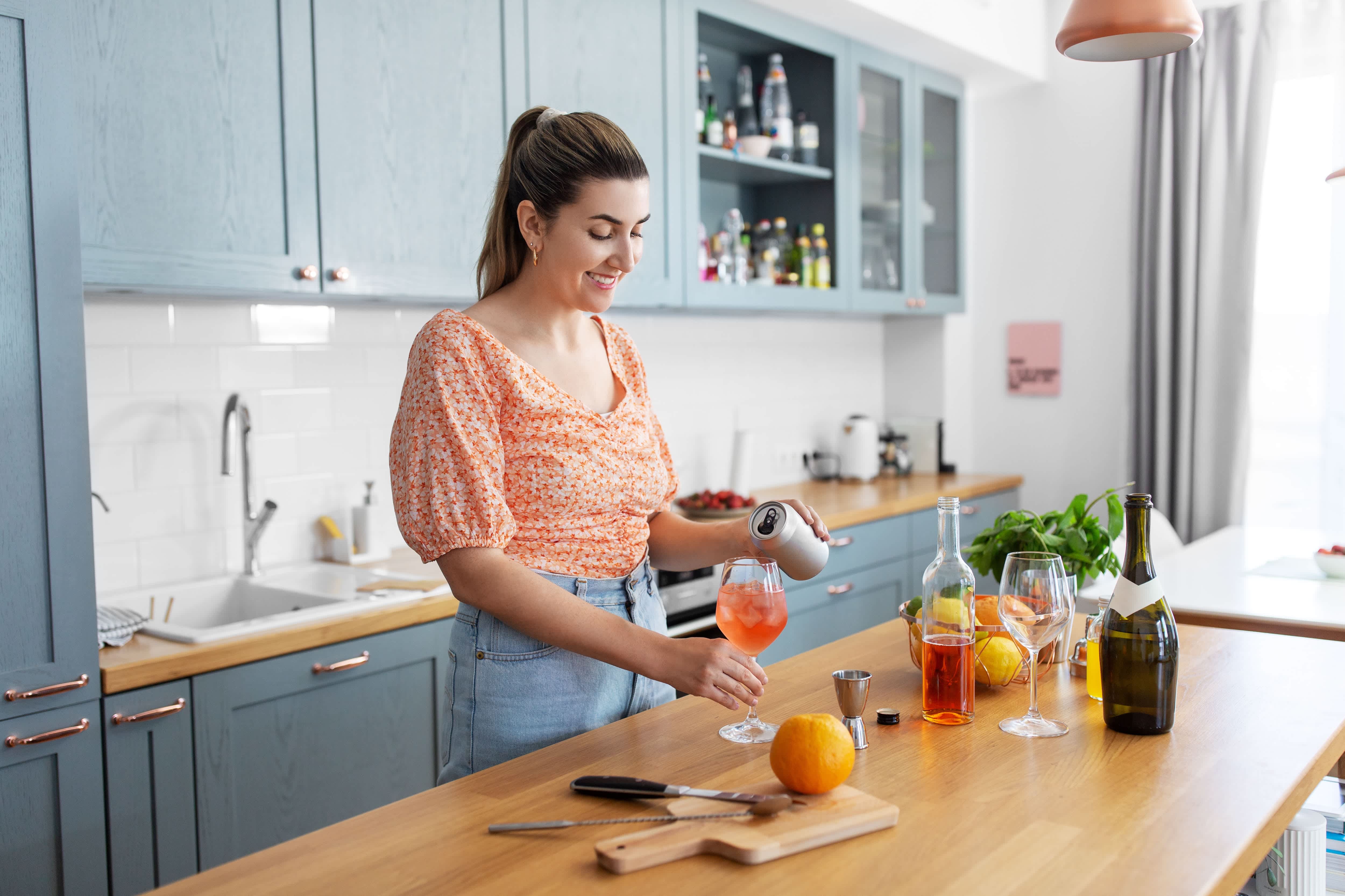 A woman mixing cocktails at a wet bar in a sunny kitchen