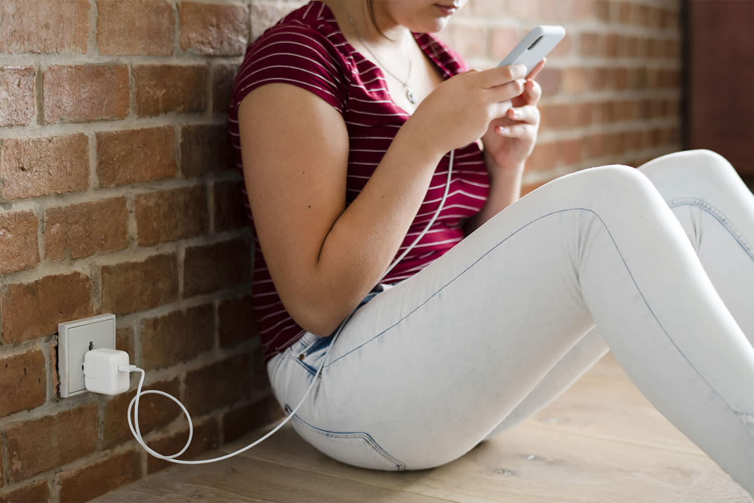 Young girl using wall charger for phone