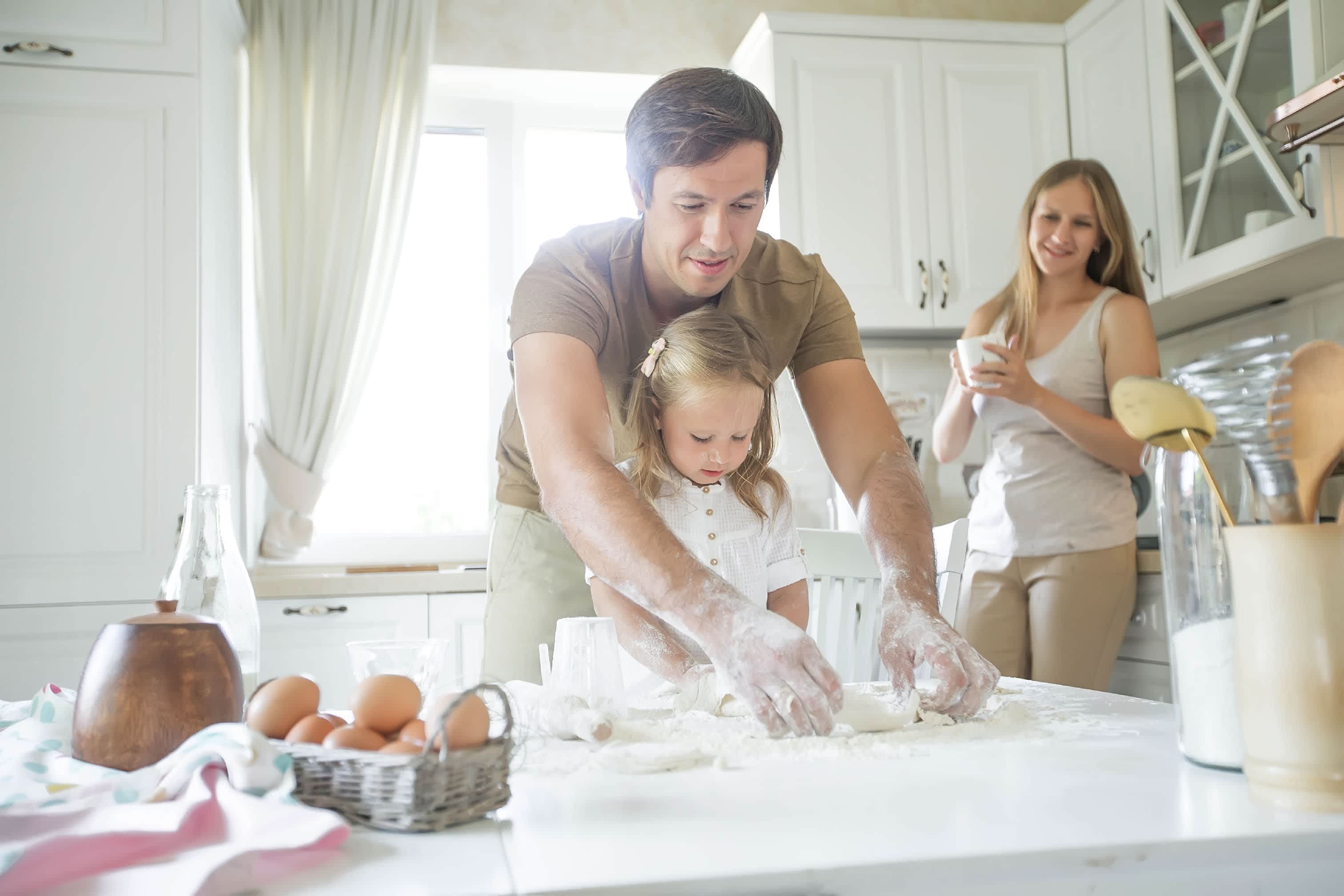 Family baking together in kitchen using countertops as workspace