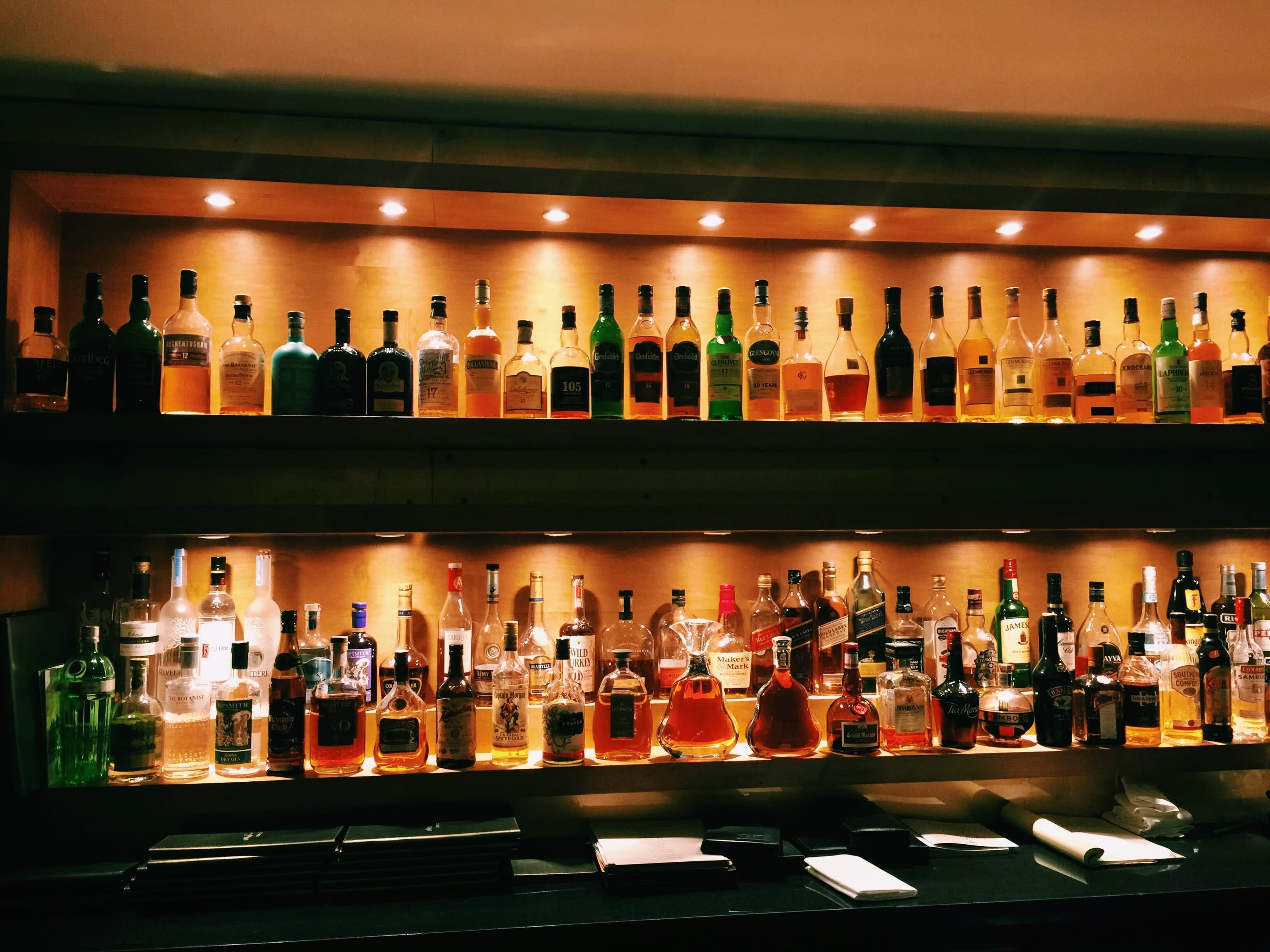 Backlit liquor bottles behind a bar