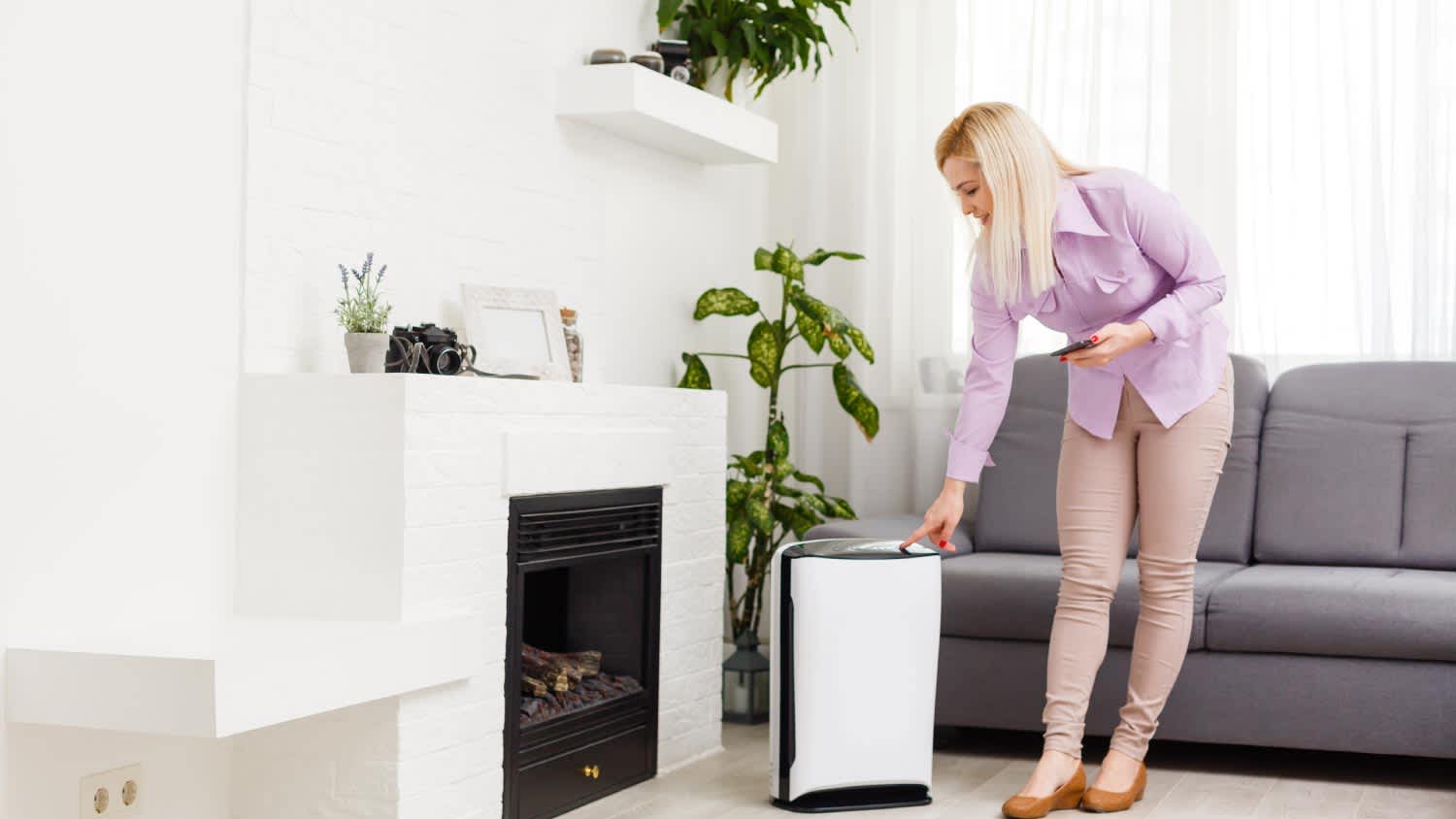 A woman turning on the air purifier