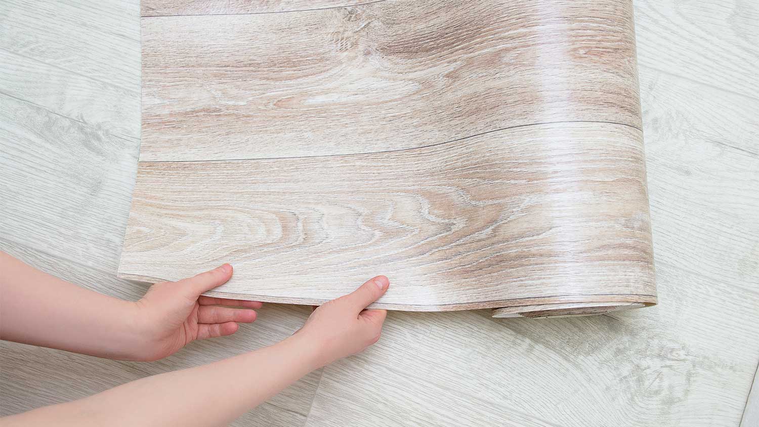 A view of someone unrolling a linoleum sheet