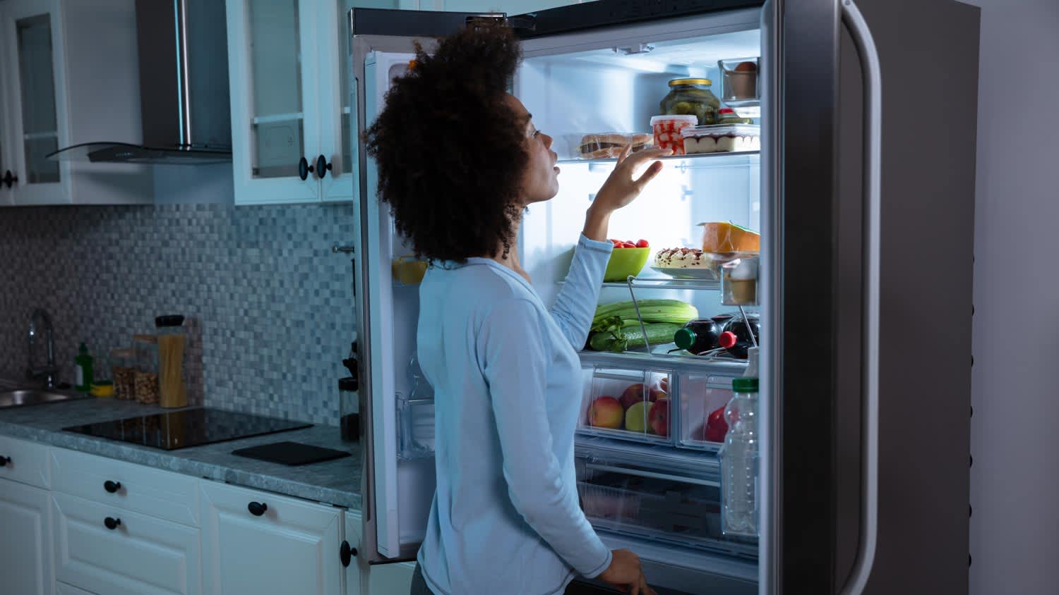 A woman setting the correct temperature in her refrigerator