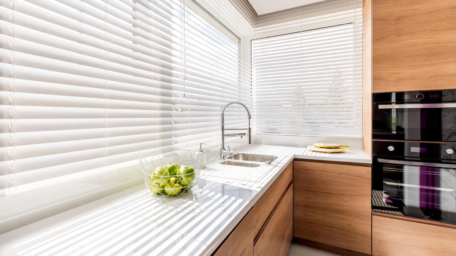 A kitchen with white window blinds