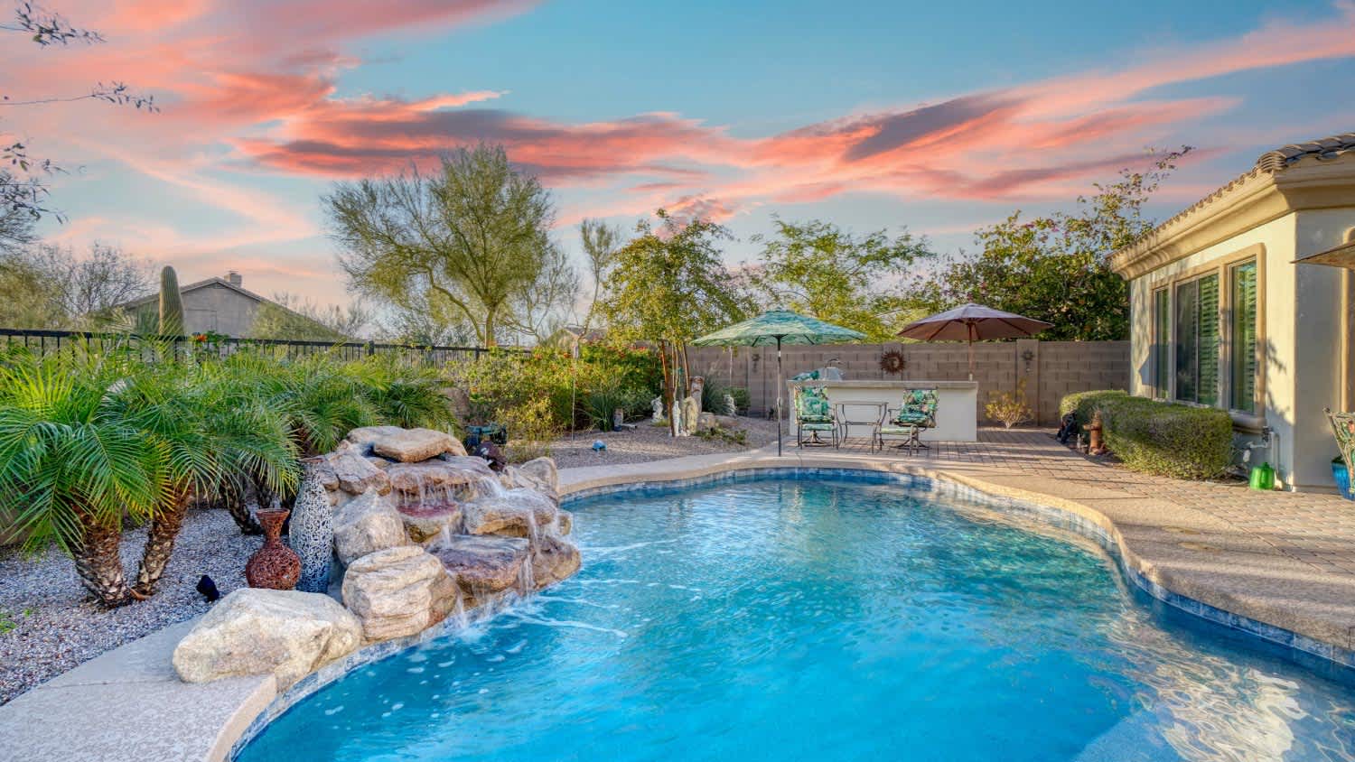 Luxury home pool at sunset with a waterfall