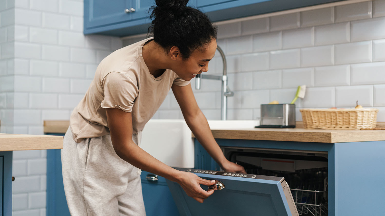 A happy woman opens a dishwasher