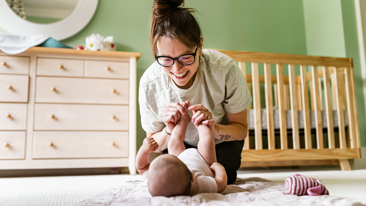 Mother in the nursery room playing on the floor with her baby