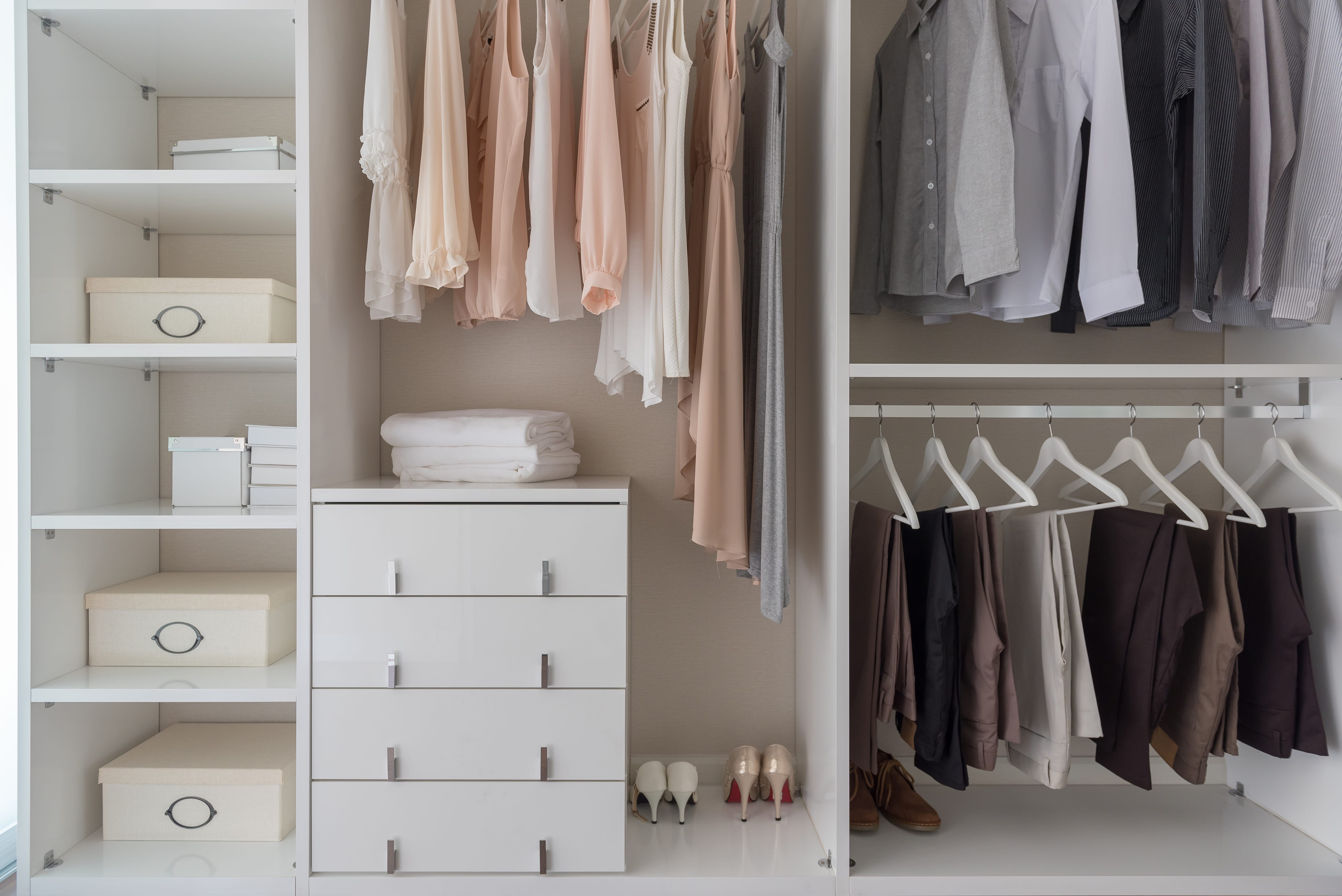 An organized closet with a small white dresser