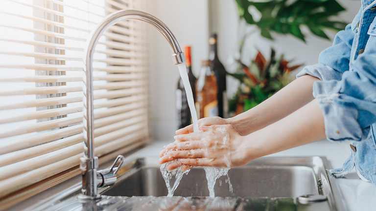 A woman washing her hands in kitchen sink