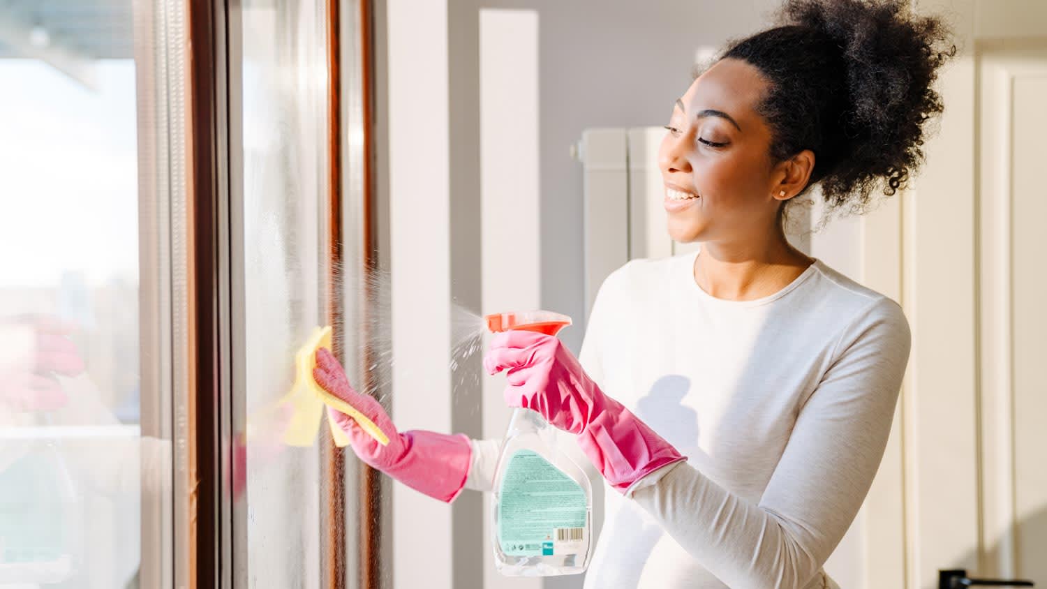 A young woman cleaning the windows of a laundry room