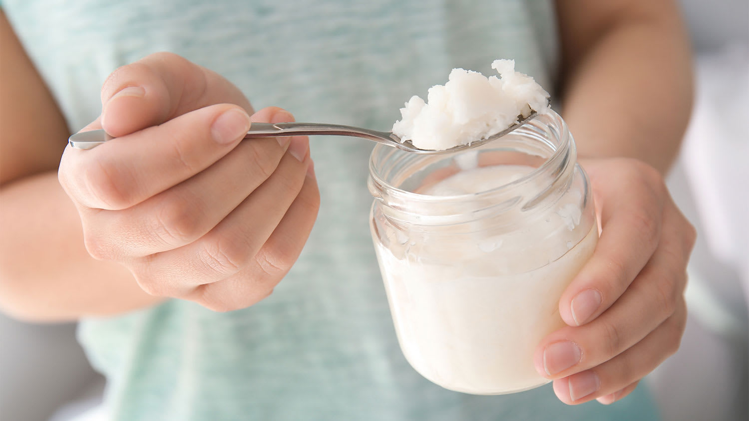A view of someone scooping coconut oil from a jar