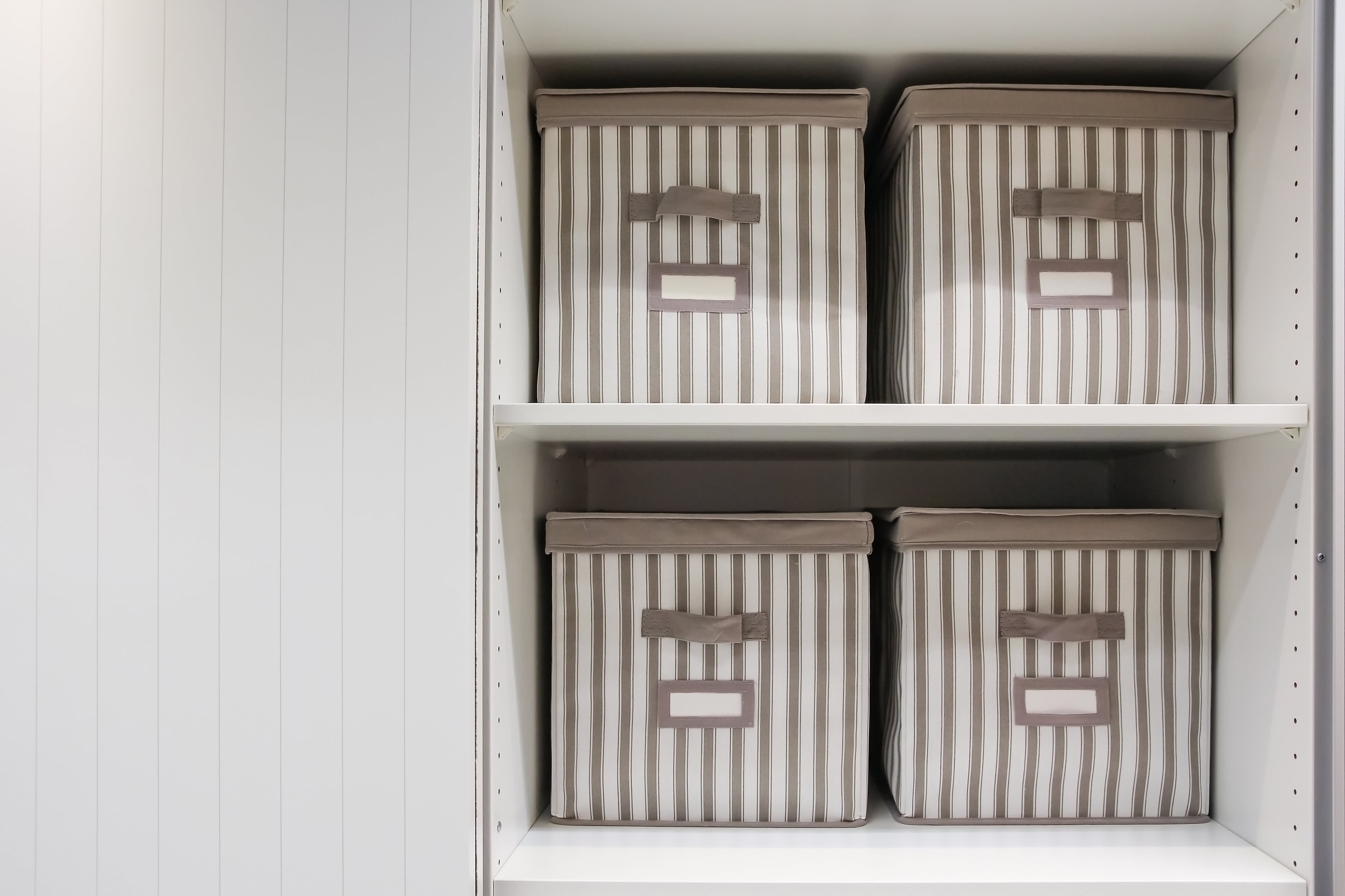 Four beige and white storage cubes stored neatly on closet shelves