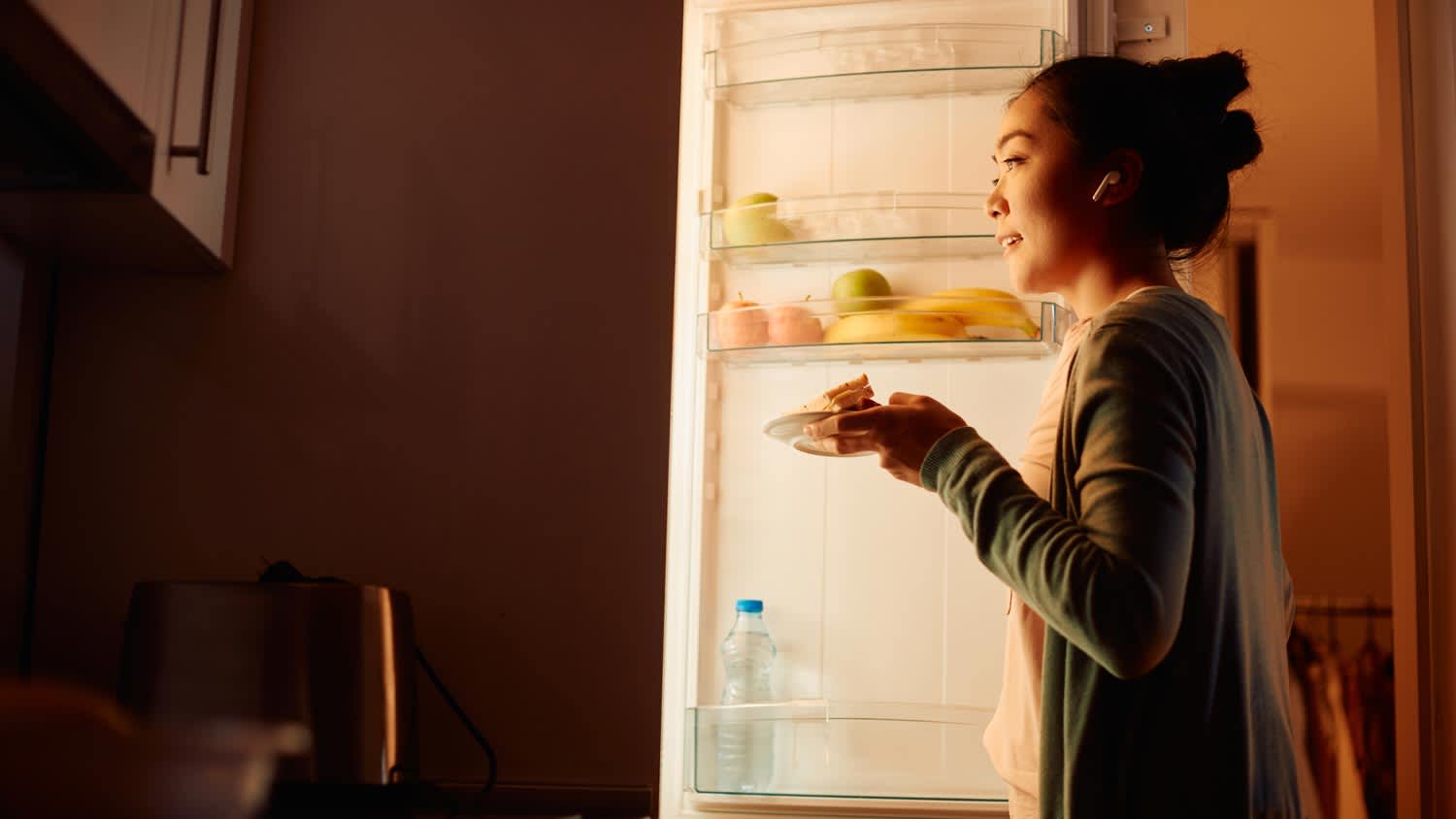 A young woman looking inside the refrigerator