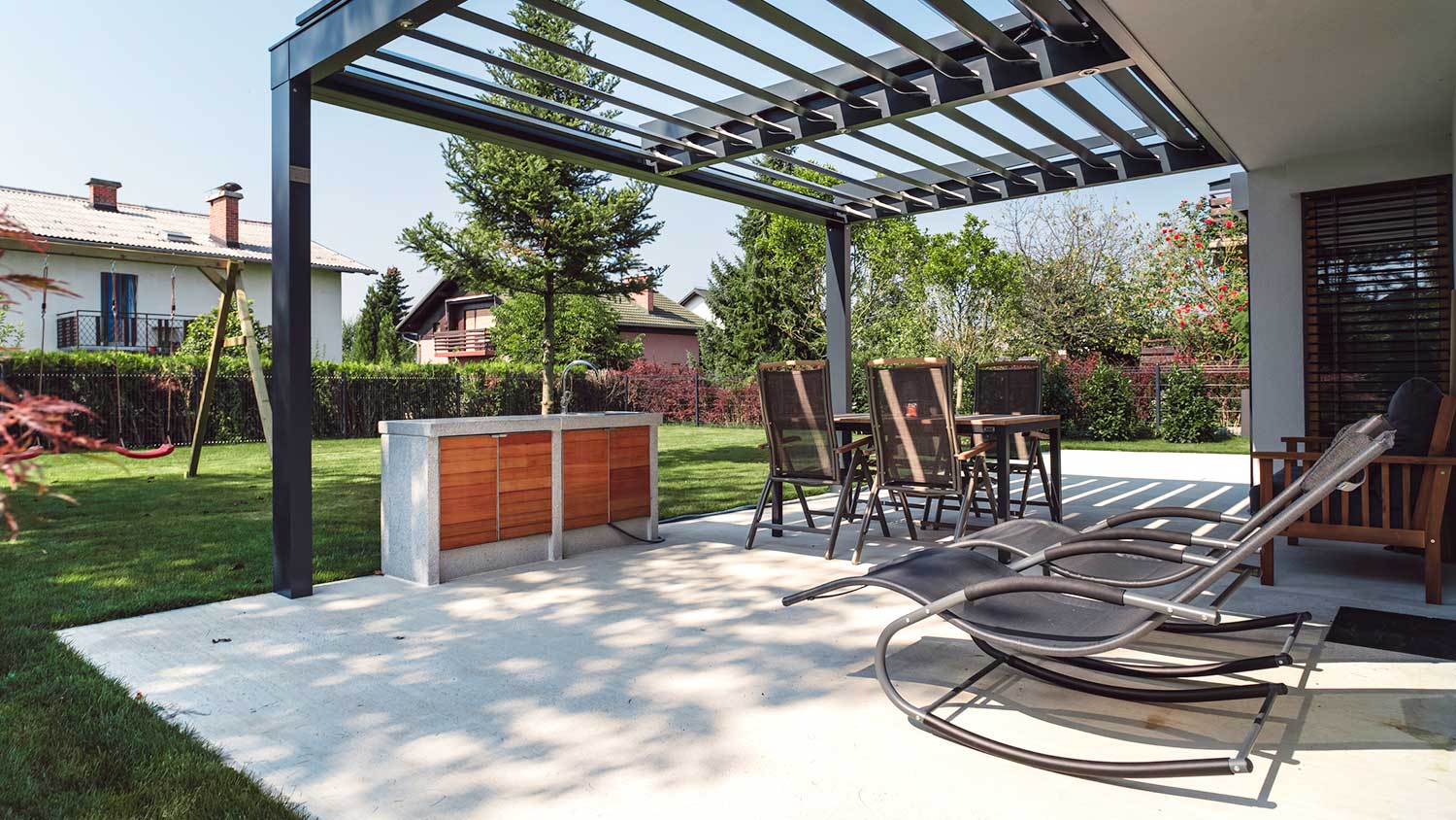 Modern concrete patio with pergola and outdoor kitchen