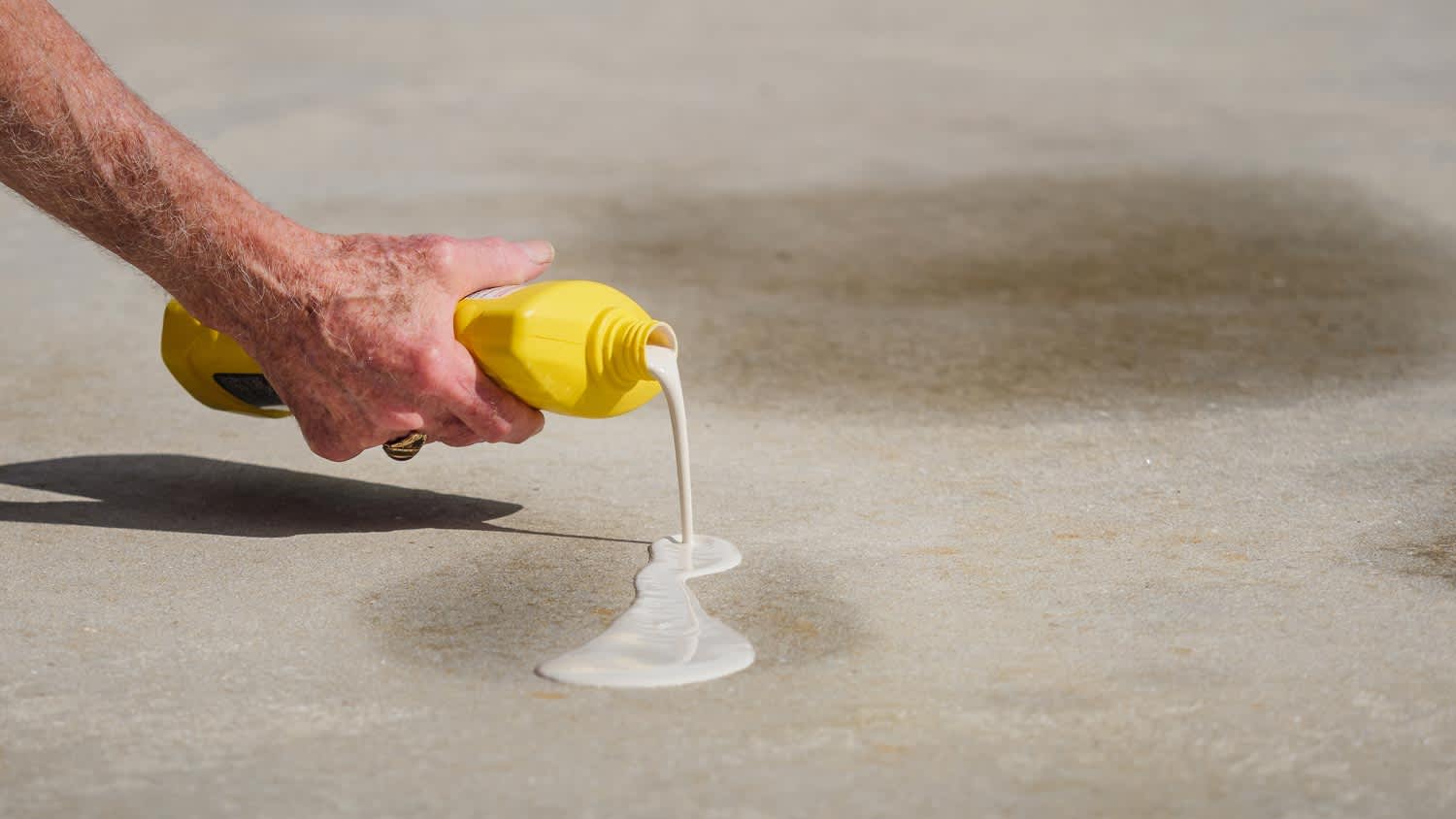 A man applying oil stain remover from driveway
