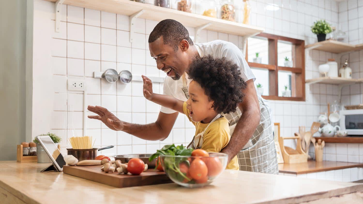 A father with his son having a video call while cooking in their kitchen