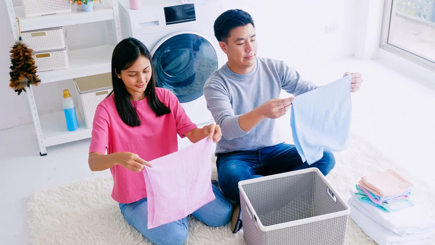 A woman and a man folding clothes after the laundry