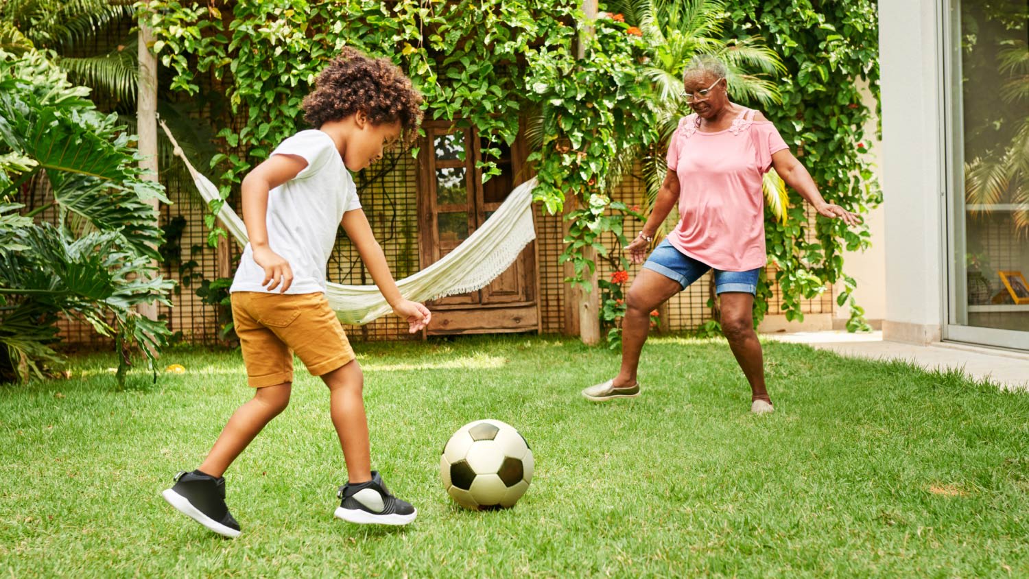 Boy playing soccer with his grandmother