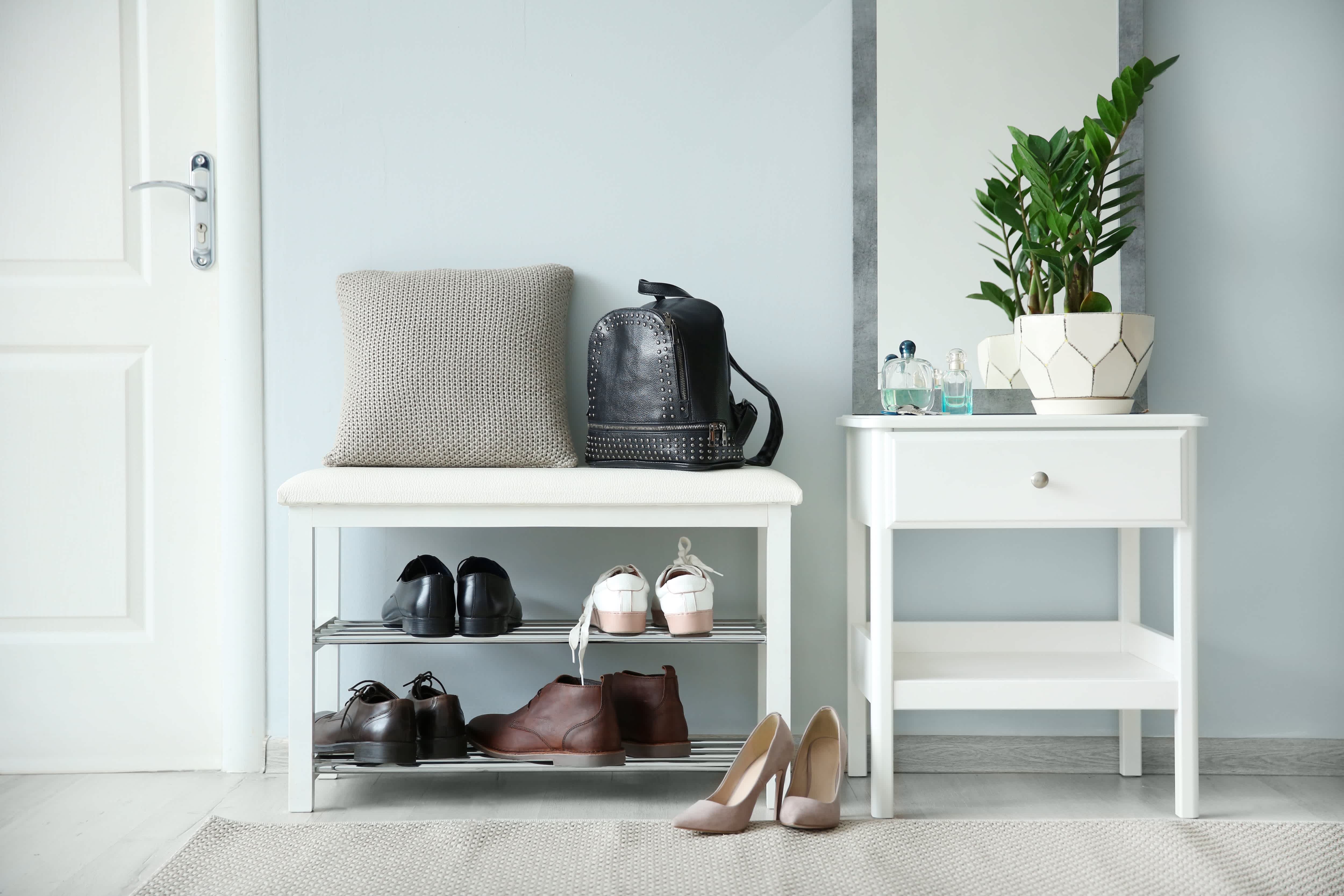 An entryway with an end table, mirror, and a bench with shoe storage