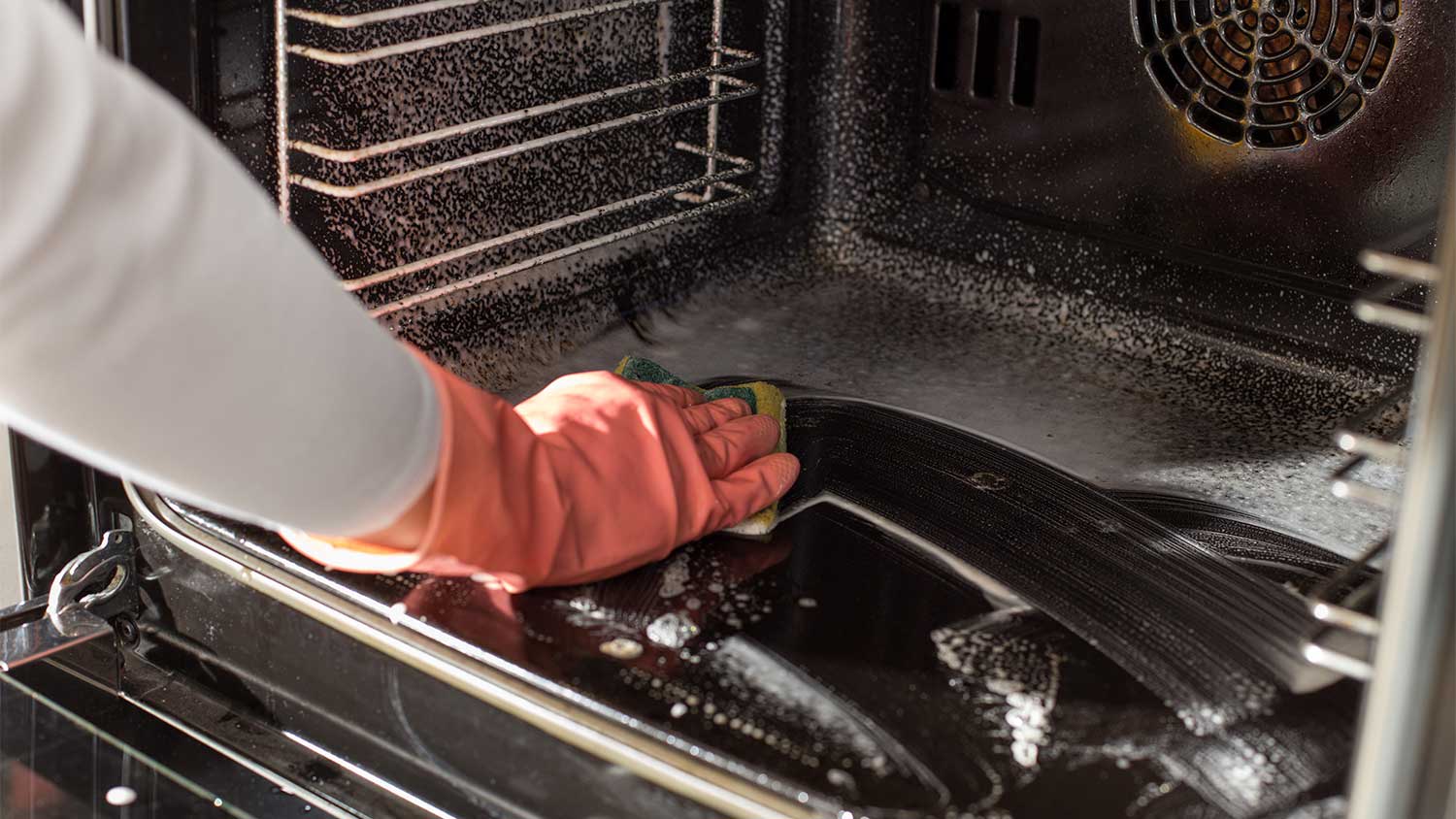 A person cleans inside an oven