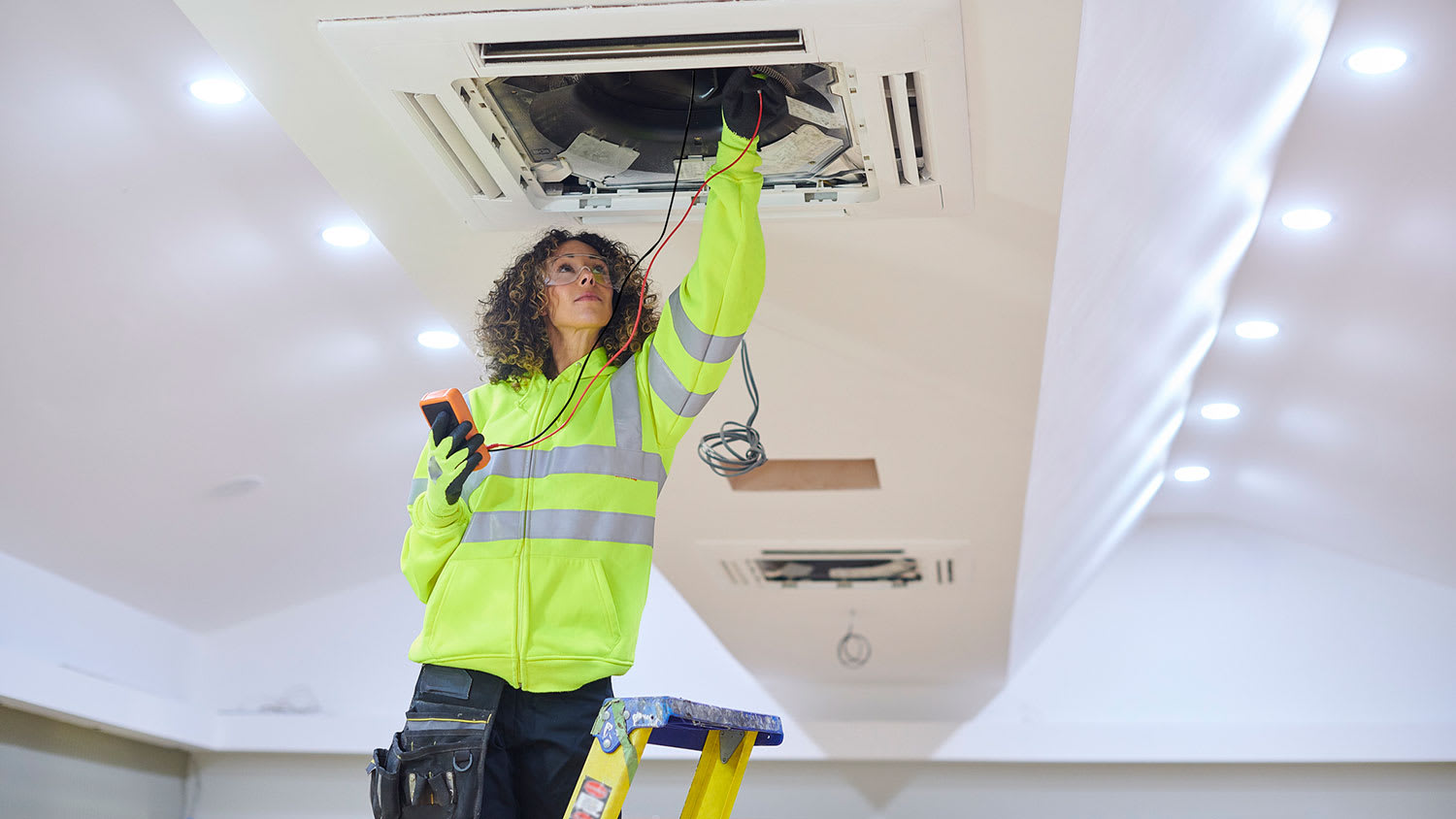 Electrician using multimeter to check ac unit