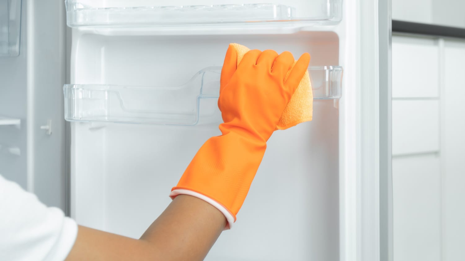 Cropped hand in glove cleaning a refrigerator