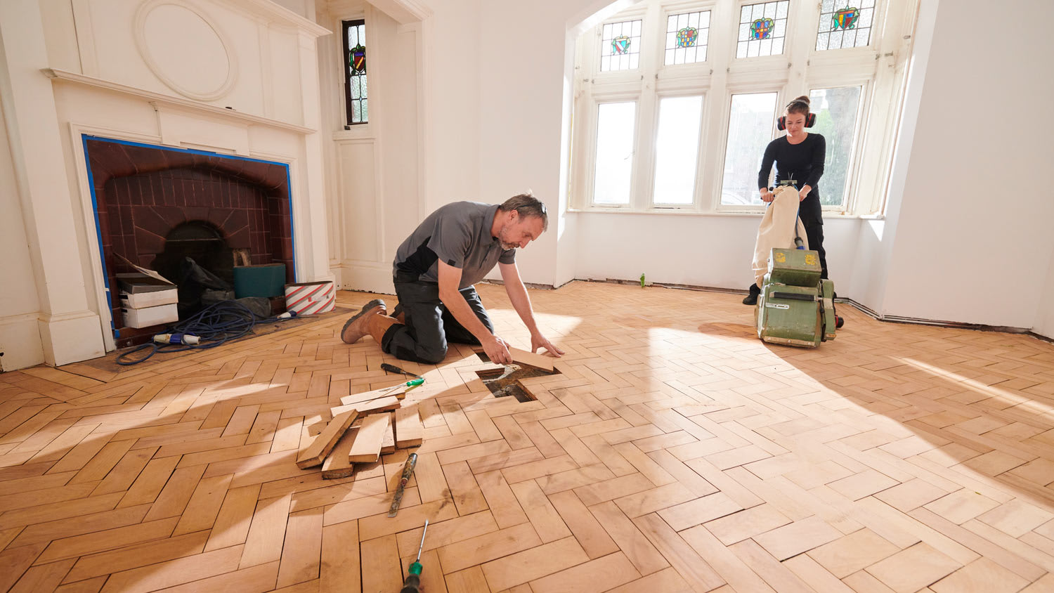 Two workers restore parquet flooring