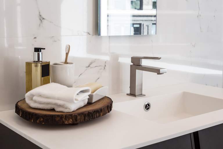 Side view of home bathroom sink and counter with bathroom products and towels neatly placed