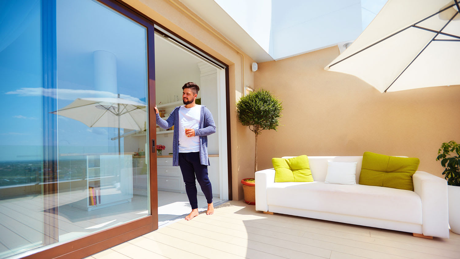 Man holding a drink is opening the patio sliding door